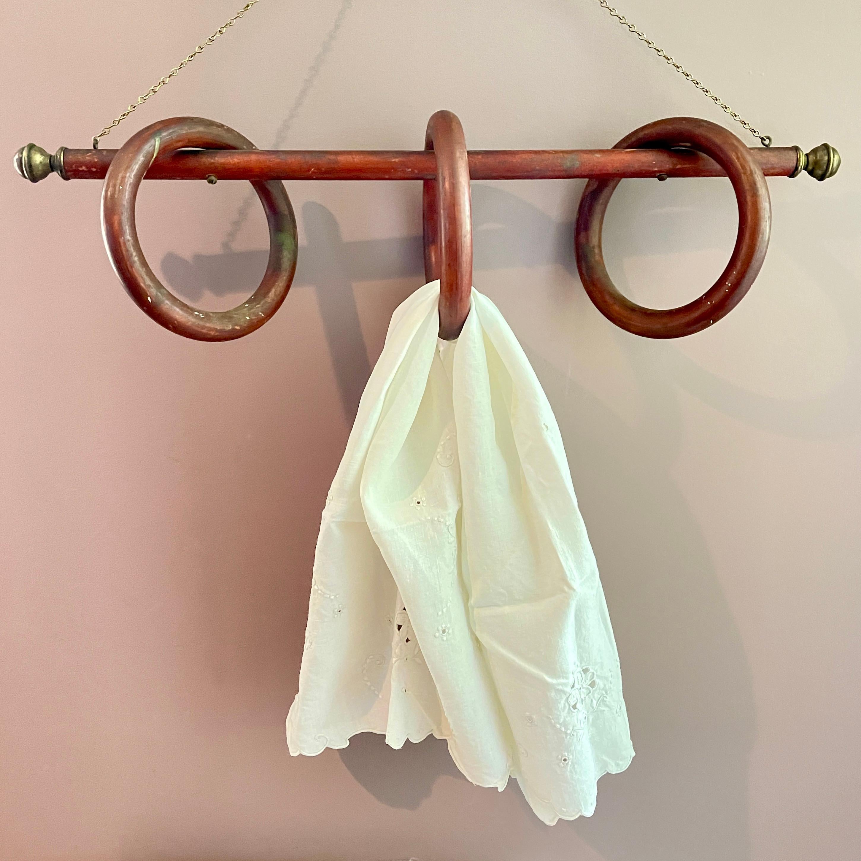 From the Belle Epoque Era, a hanging Three Ring Fruit Wood and Brass Towel Rack, France, circa 1880-1900.

A long bar hangs from a brass chain.
The bar is finished with brass end caps.
Three wooden rings are screwed to the bar.
The rings can be