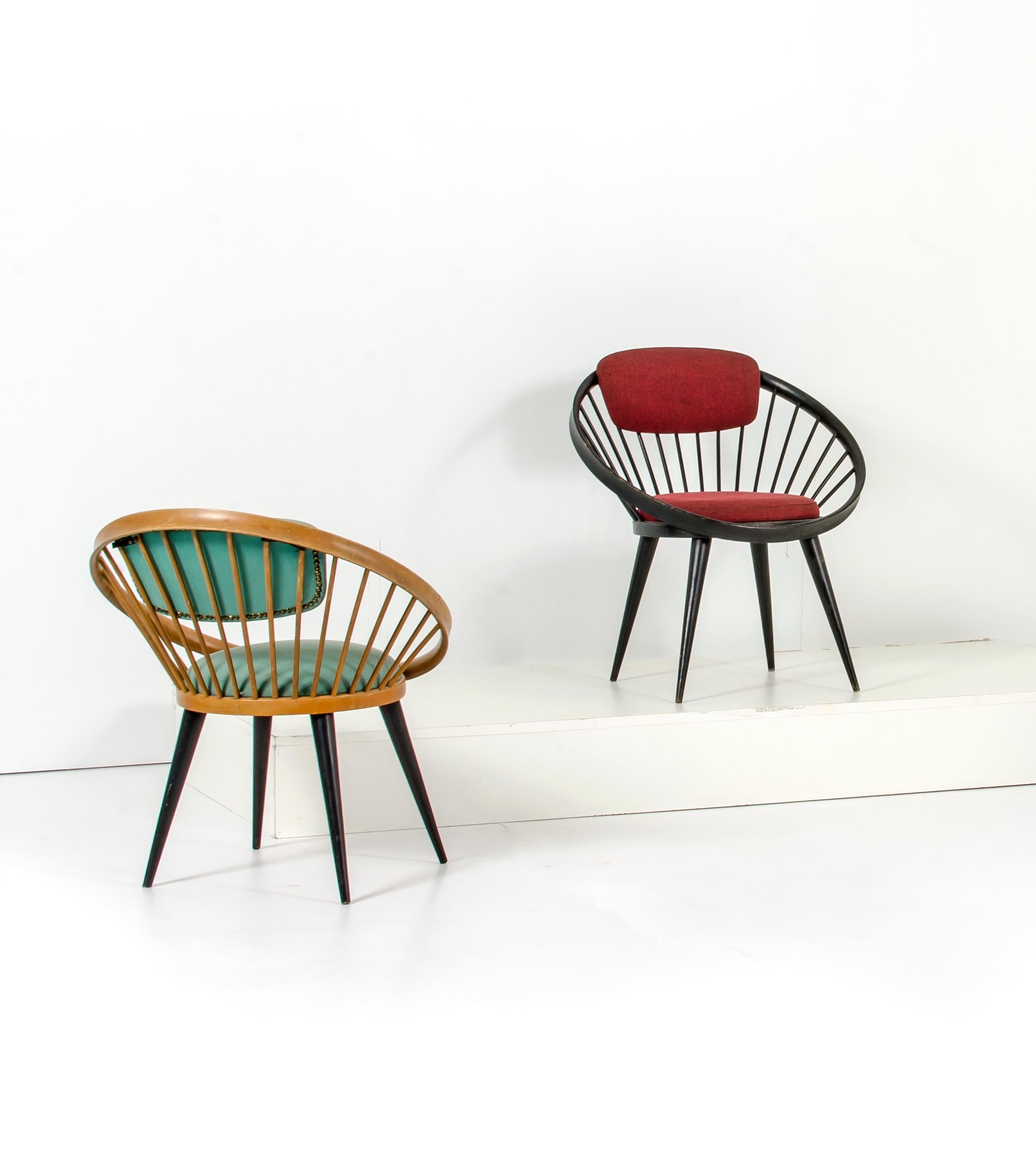 Three Yngve Ekström Mid-Century circle lounge chairs. Two of those chairs are made of bicolor lacquered beechwood and have green colored leather seats while the last one is in ebonized wood with red leather seat and backrest.

