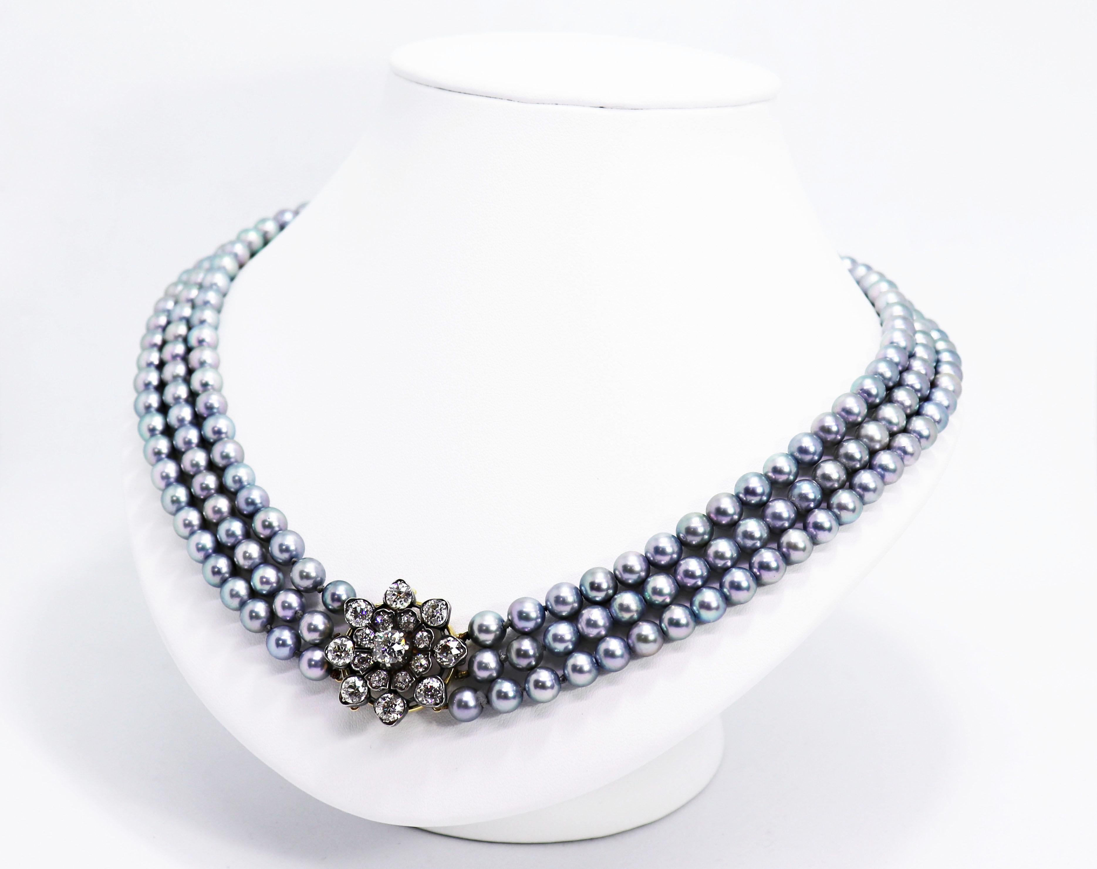 Exquisite 1920's necklace featuring three rows of 216 silver grey dyed Akoya pearls, strung to a handmade old European cut diamond set clasp. The diamonds have a total approximate weight of 5.41 carats with the centre stone weighing an estimated