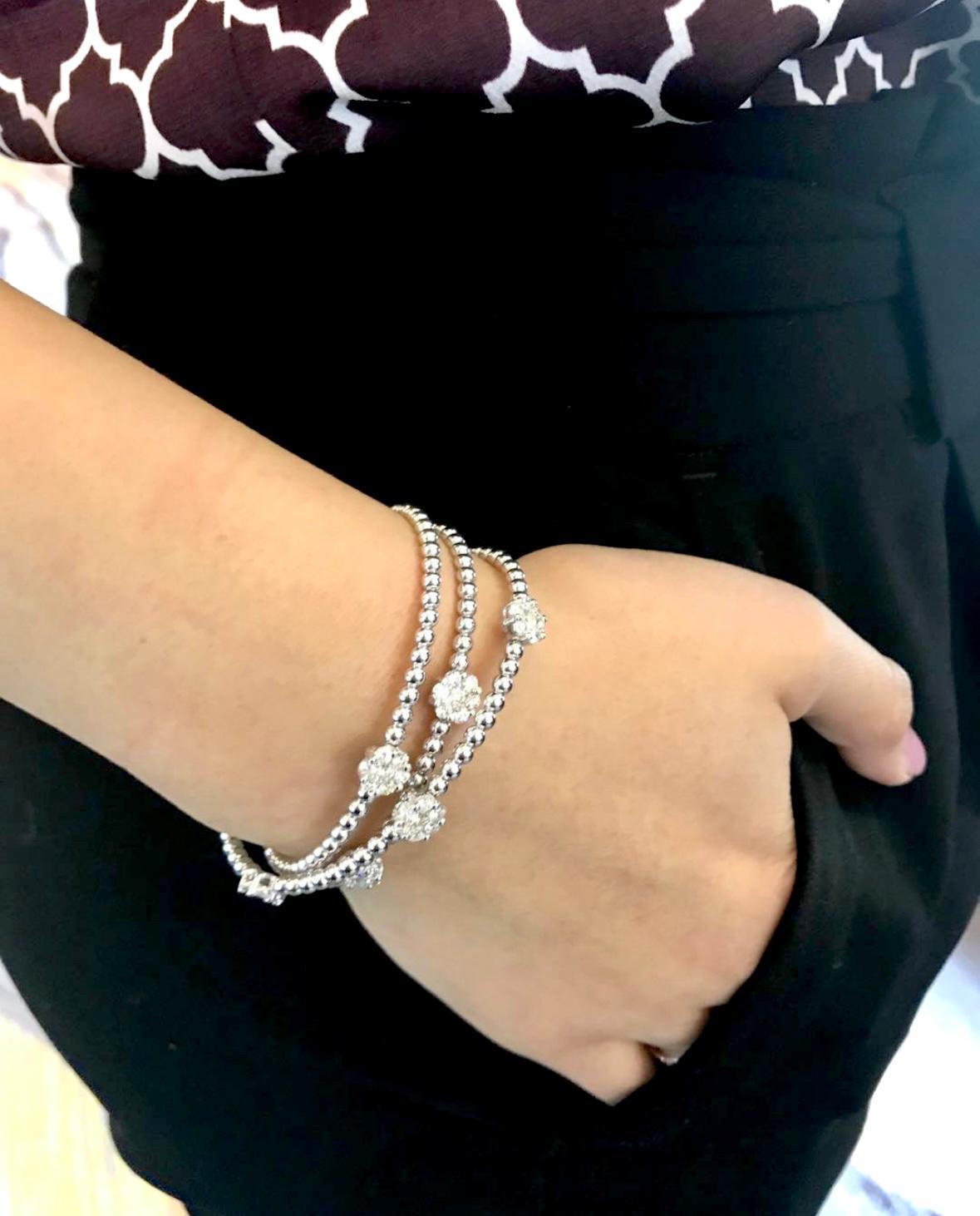 Dieser elegante, in Italien handgefertigte Armreif mit dreireihigem Diamantencluster zeigt ein raffiniertes Blumenmotiv, das mit außergewöhnlicher Brillanz zum Leben erweckt wird. Das Design besteht aus einer Reihe von Diamantblüten, von denen jede