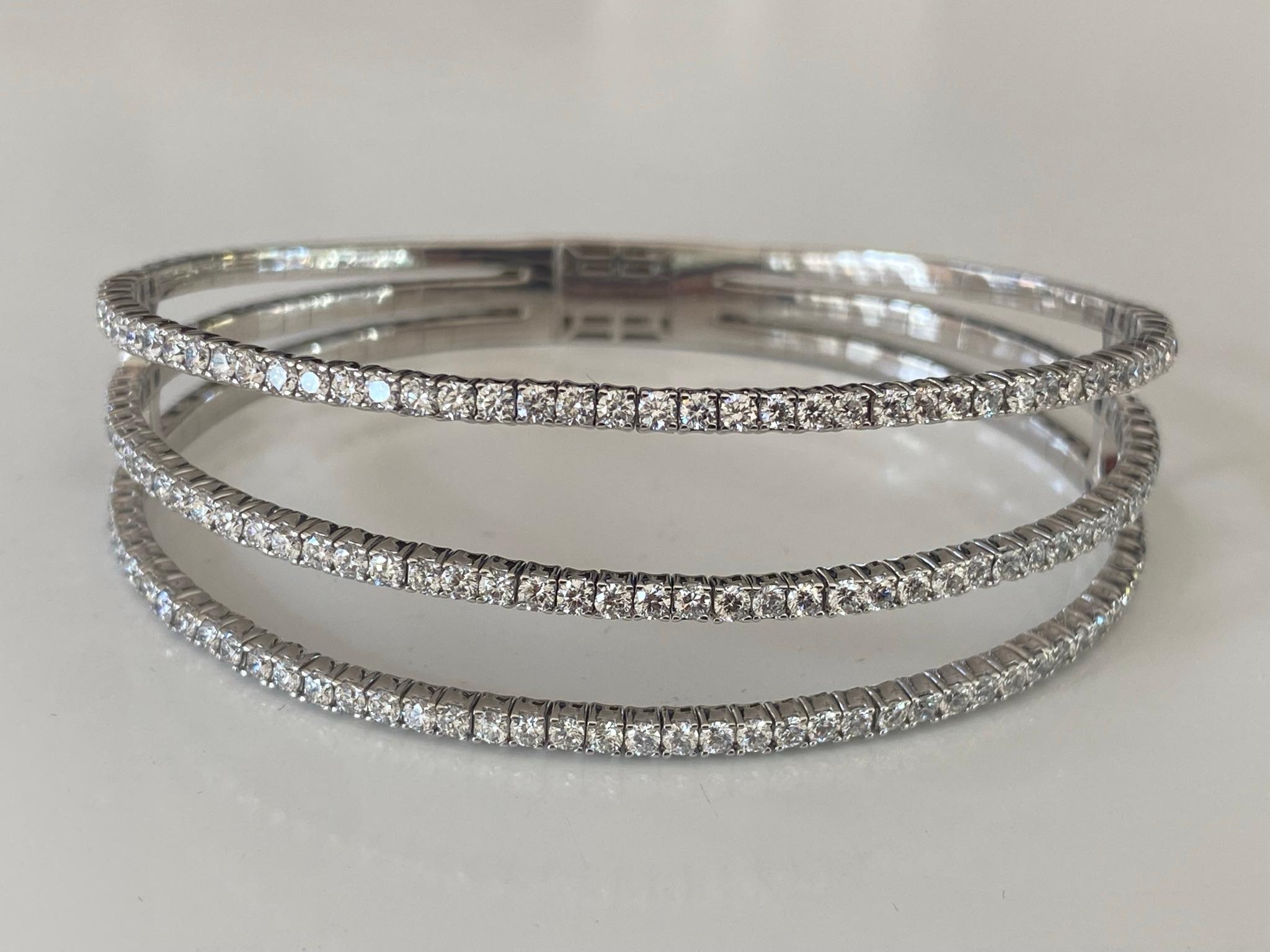 Crafted from 14kt white gold, this flexible bangle bracelet features 141 round diamonds, G color, VS-SI clarity that glisten over three rows. The diamonds total 3.70 carats and the bracelet measures 7 inches. 

