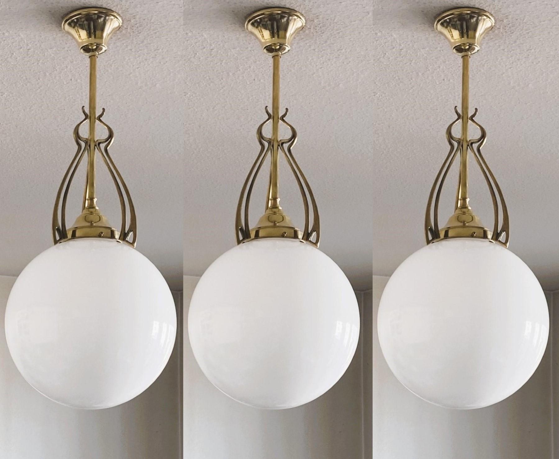Set of three wonderful and rare ball pendants from the transition period from Art Nouveau to Art Deco, Scandinavia, 1920-1930. Hand-blown opaline glas sphere globes with beautifuly elaborate brass galery.
One porcelain E27 light socket for a large