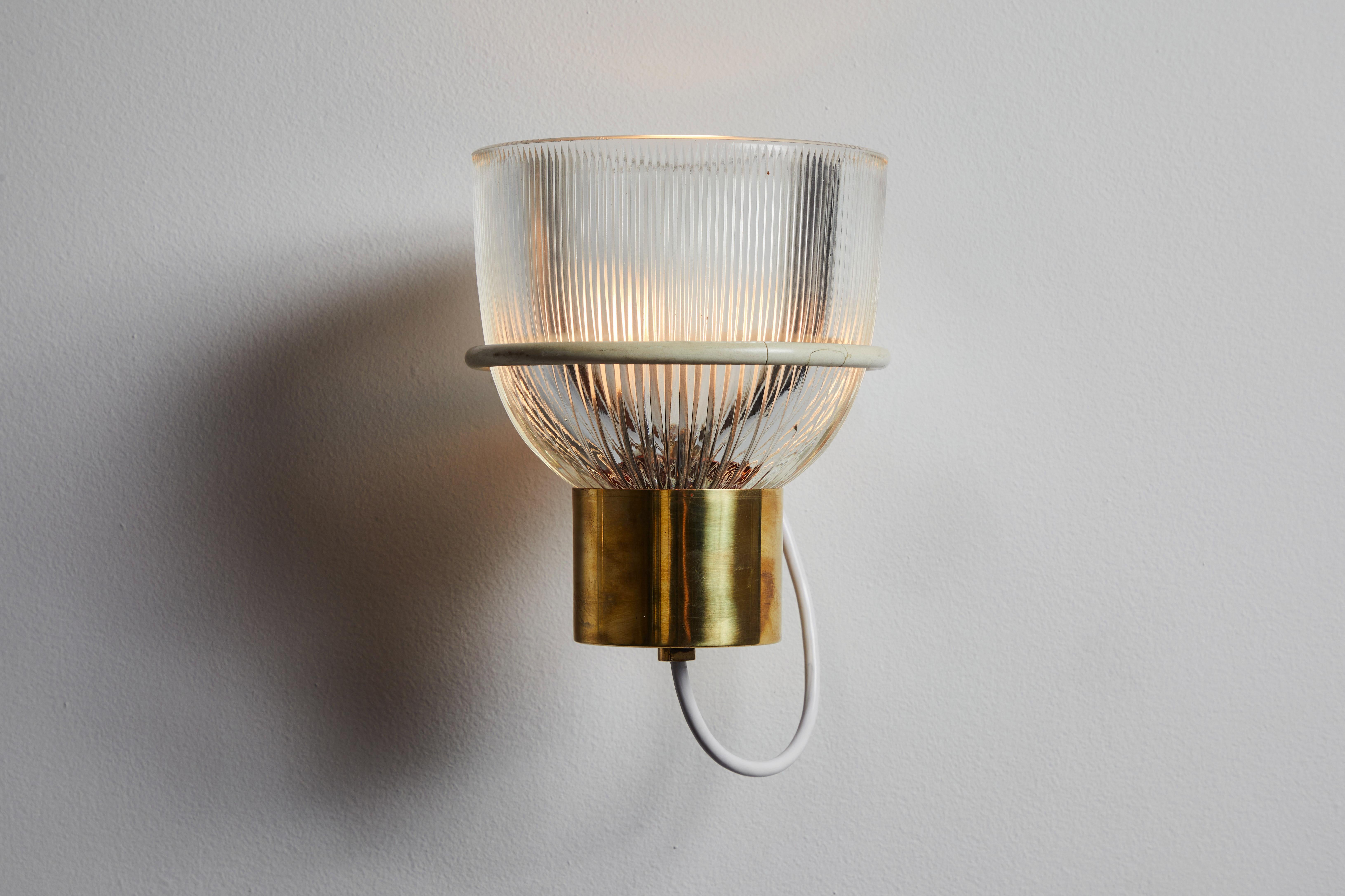 One sconce by Tito Agnoli for Oluce . Designed and manufactured in Italy, circa 1950s. Glass, brass, custom brass backplates. Rewired for U.S. standards. We recommend one E27 100w maximum bulb. Bulbs provided as a one time courtesy. Priced and sold