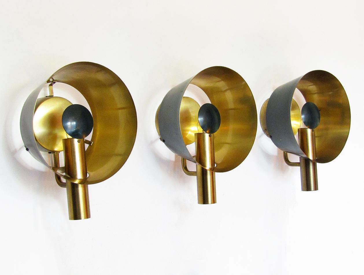 A set of three sculptural 1960s brass wall lights by Danish makers Lyfa.

Evoking 20th century aeronautics, the lights are made of brass with racing green lacquer. The brass reflectors emit spectacular golden light.

They are in excellent