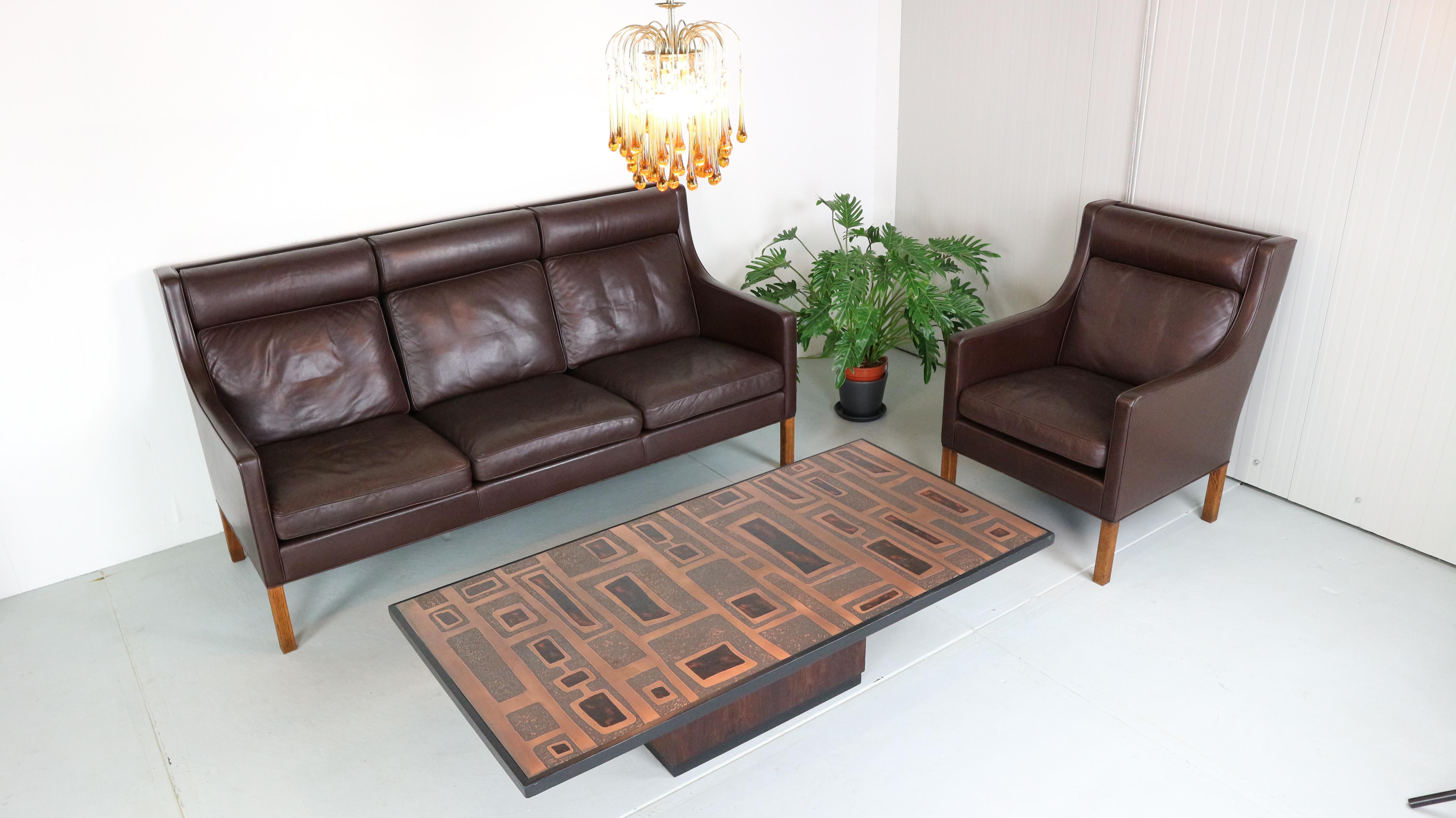 2433 model deep-brown three-seat leather sofa on the solid oak legs and 2432 model wingback chair was designed by Børge Mogensen in the 1960s. The set was made in the 1970s by Fredericia Furniture in Denmark and is very comfortable, remaining in a