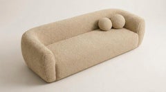 Sofá de tres plazas en color champán con tejido bouclé. Brazos redondeados, modernismo orgánico de mediados de siglo