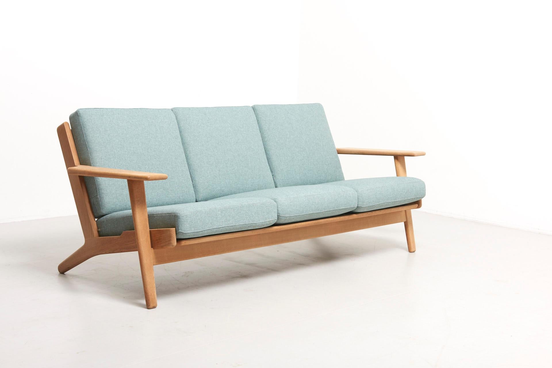 Three-seat sofa designed by Hans J. Wegner in 1953. Model GE-290, produced by GETAMA in Denmark.
Solid oak frame with new cushions upholstered in soft blue felt.
 