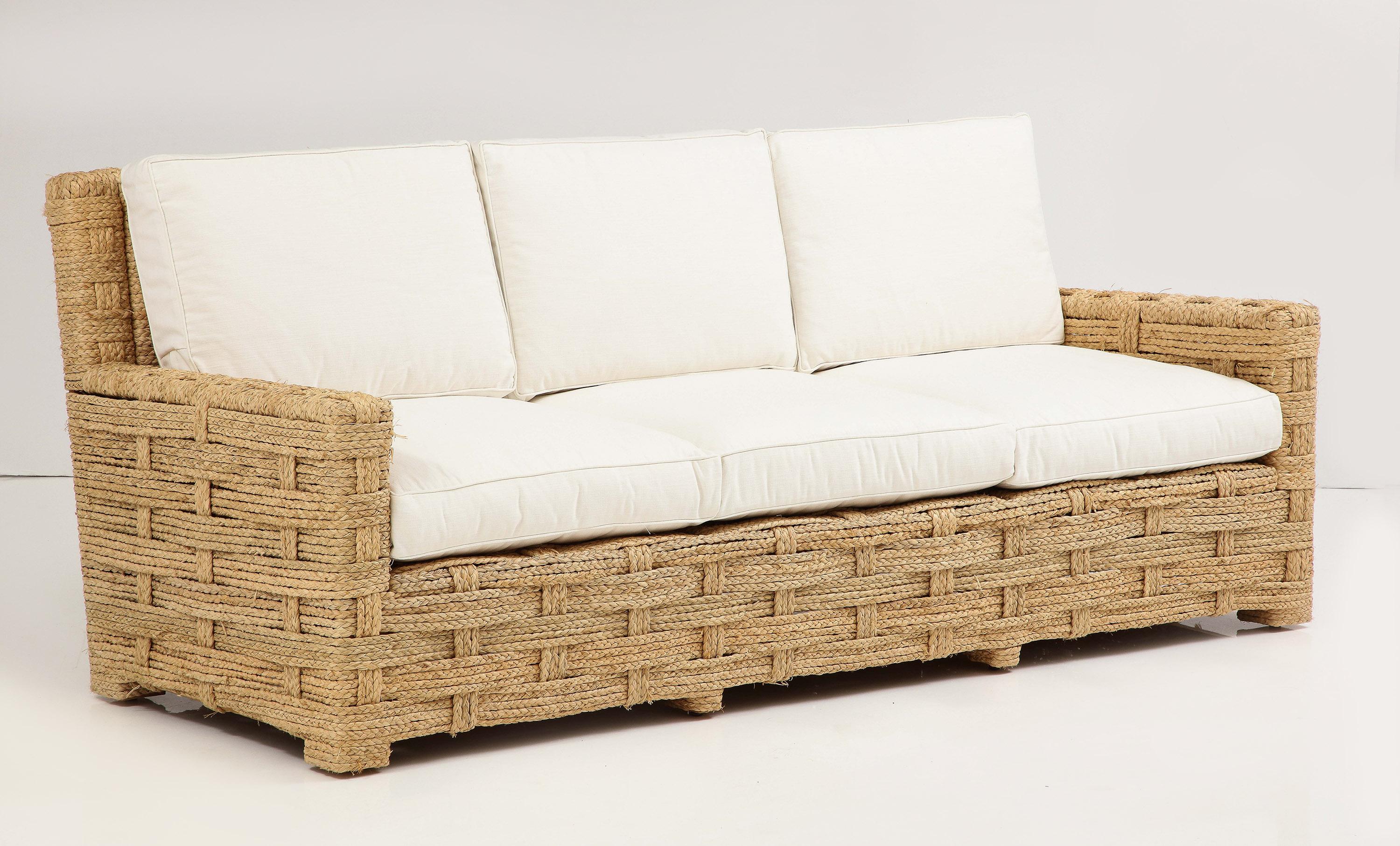 Consisting of a three-seat sofa and pair of arm chairs,
all in very fine original condition, the whole wrapped in braided raffia over an oak frame. 
Chairs: 34.75H x 28W x 34.75D - Seat H. 17.32
