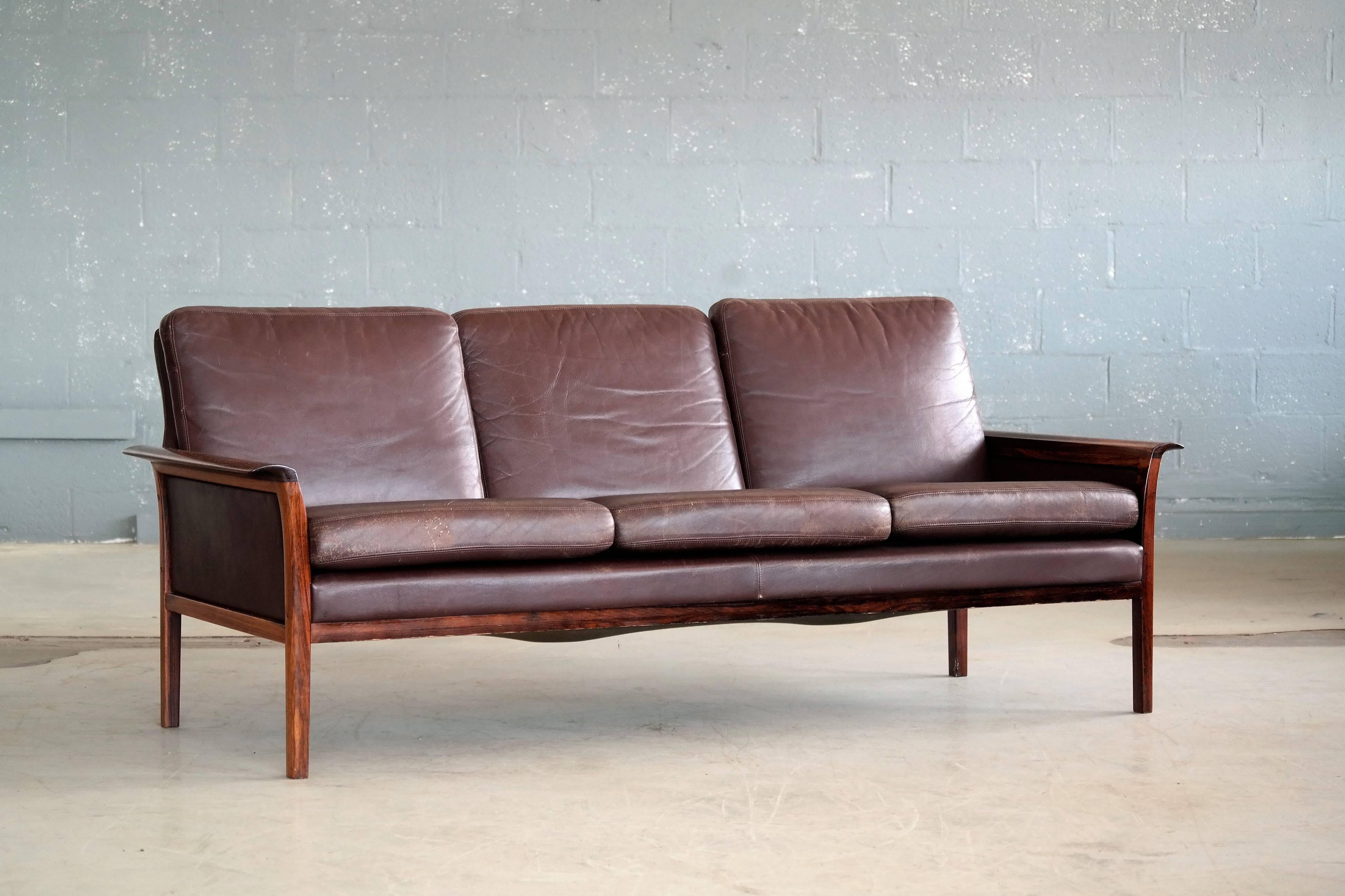 Beautiful Hans Olsen and Knut Saeter designed three-seat sofa in supple cordovan leather and rosewood frame manufactured by Vatne of Norway in the late 1960s. Olsen's characteristic design with finely polished rolled wing shaped armrests in solid