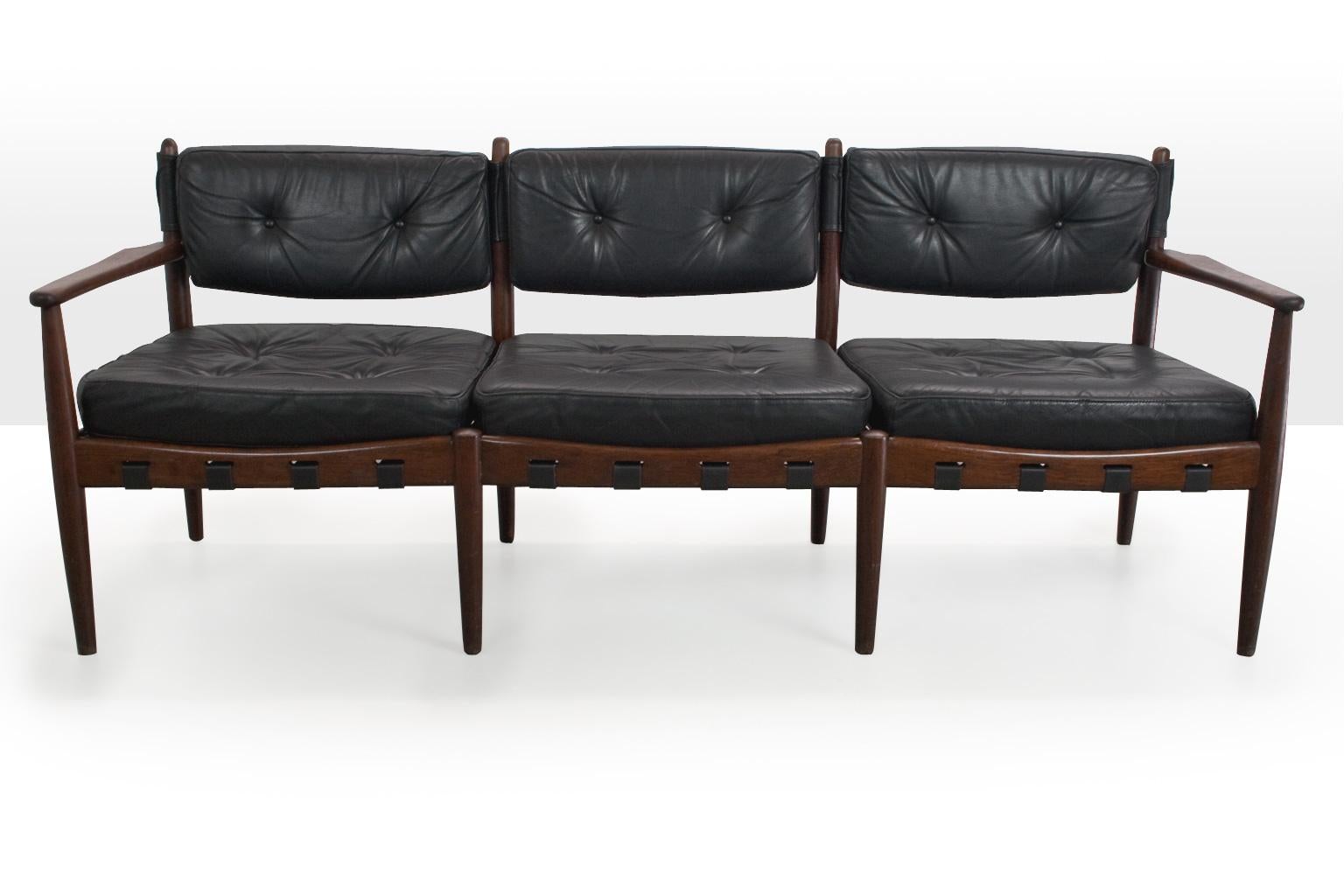 A three-seat Scandinavian modern sofa by Eric Merthen for Swedish IRE AB Skyllingaryd. This Brazilian inspired sofa features a frame of solid teak and padded black leather cushions. The webbing under the seats is renewed, the comfort and leather is