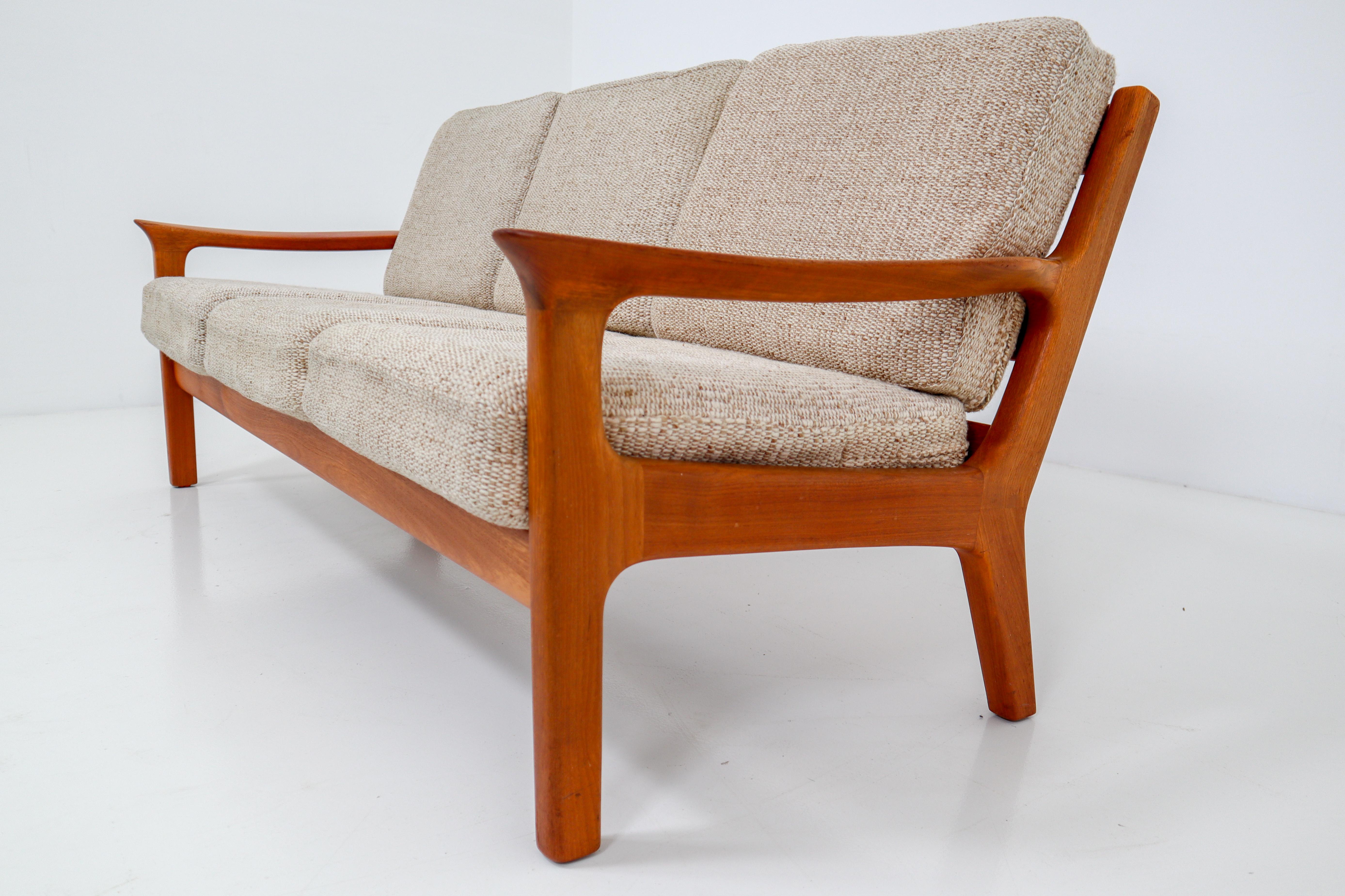Three-seat sofa in solid teak and cushions designed by the Danish designer Juul Kristensen and manufactured by Glostrup Furniture Factory in the 1960s. The cushions are upholstered with a sandy colored high quality original fabric. The teak wooden