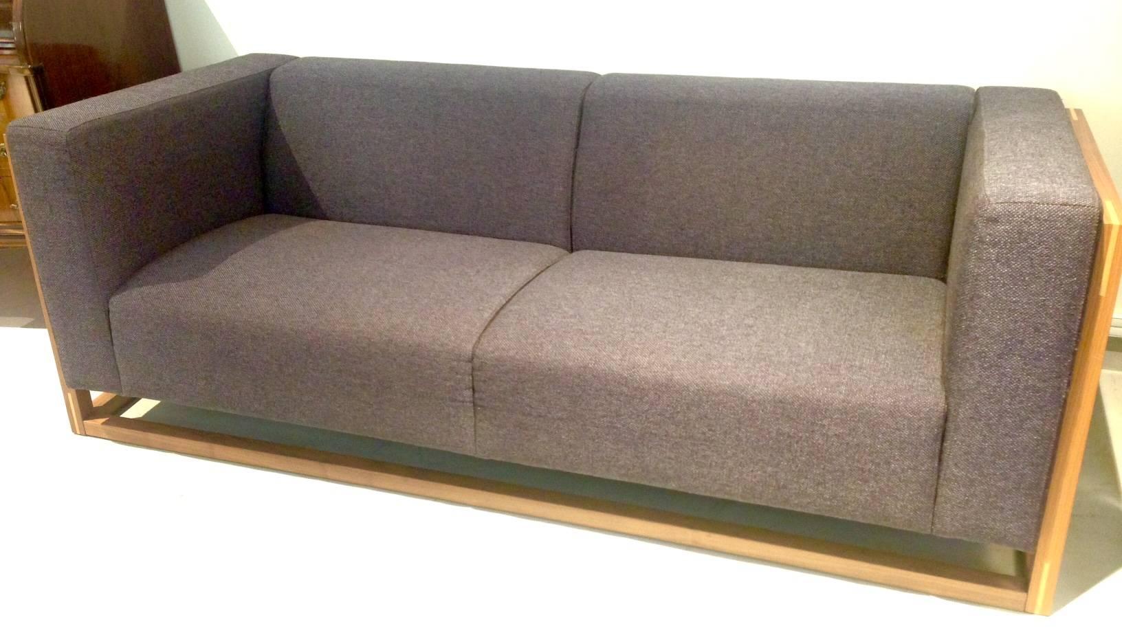 Angular three-seat sofa featuring solid walnut frame with pale wood inlay, produced by Bolia in Denmark. Thick dark bluish-grey woven fabric upholstery. Beautiful Minimalist shape, comfortable seat.