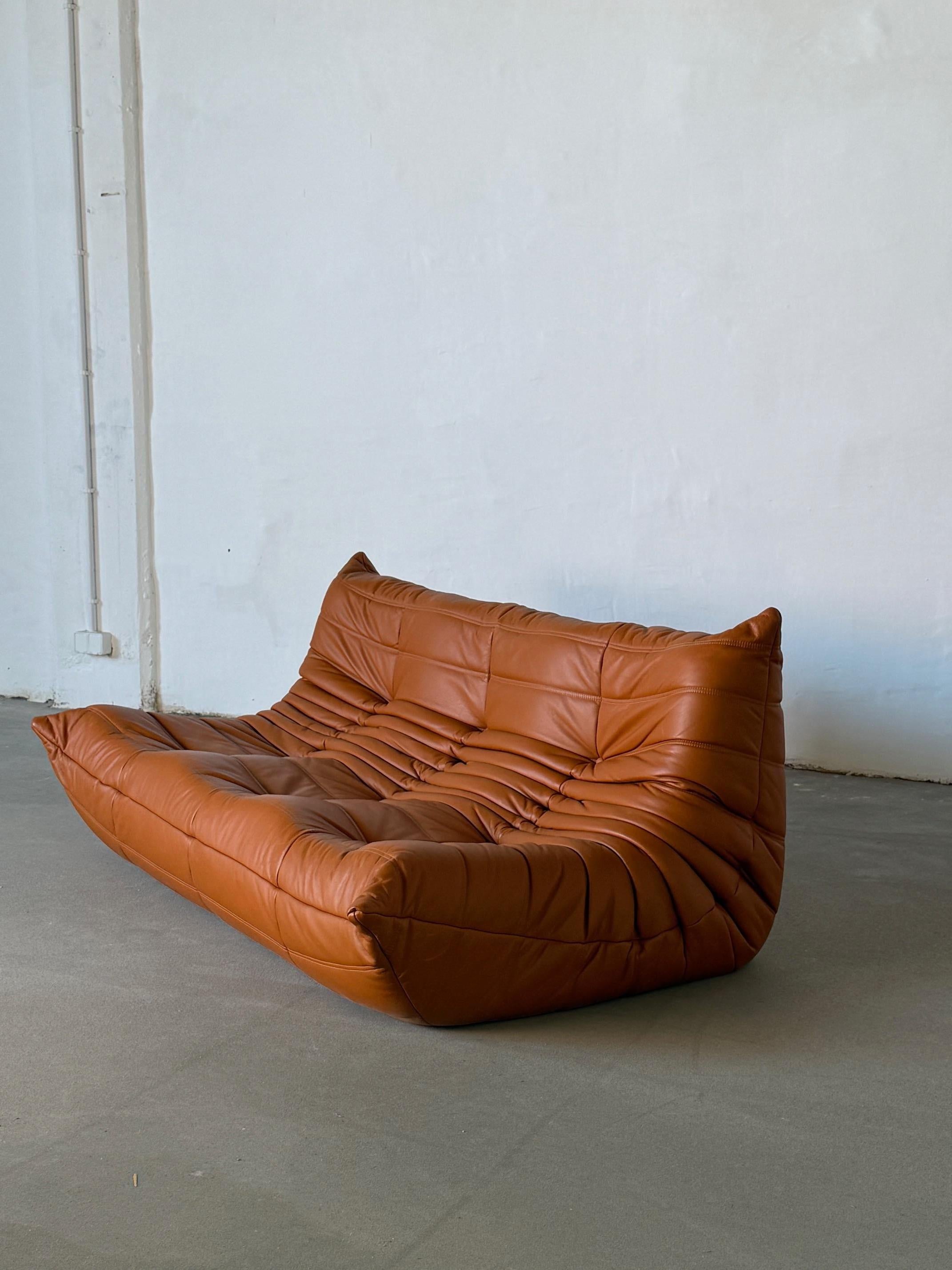 FREE LOCAL DELIVERY WITHIN NEW YORK CITY

An iconic three-seat Togo sofa designed by Michel Ducaroy for Ligne Roset, originally introduced in 1973. This example has been restored and newly reupholstered in supple natural leather in a rich caramel