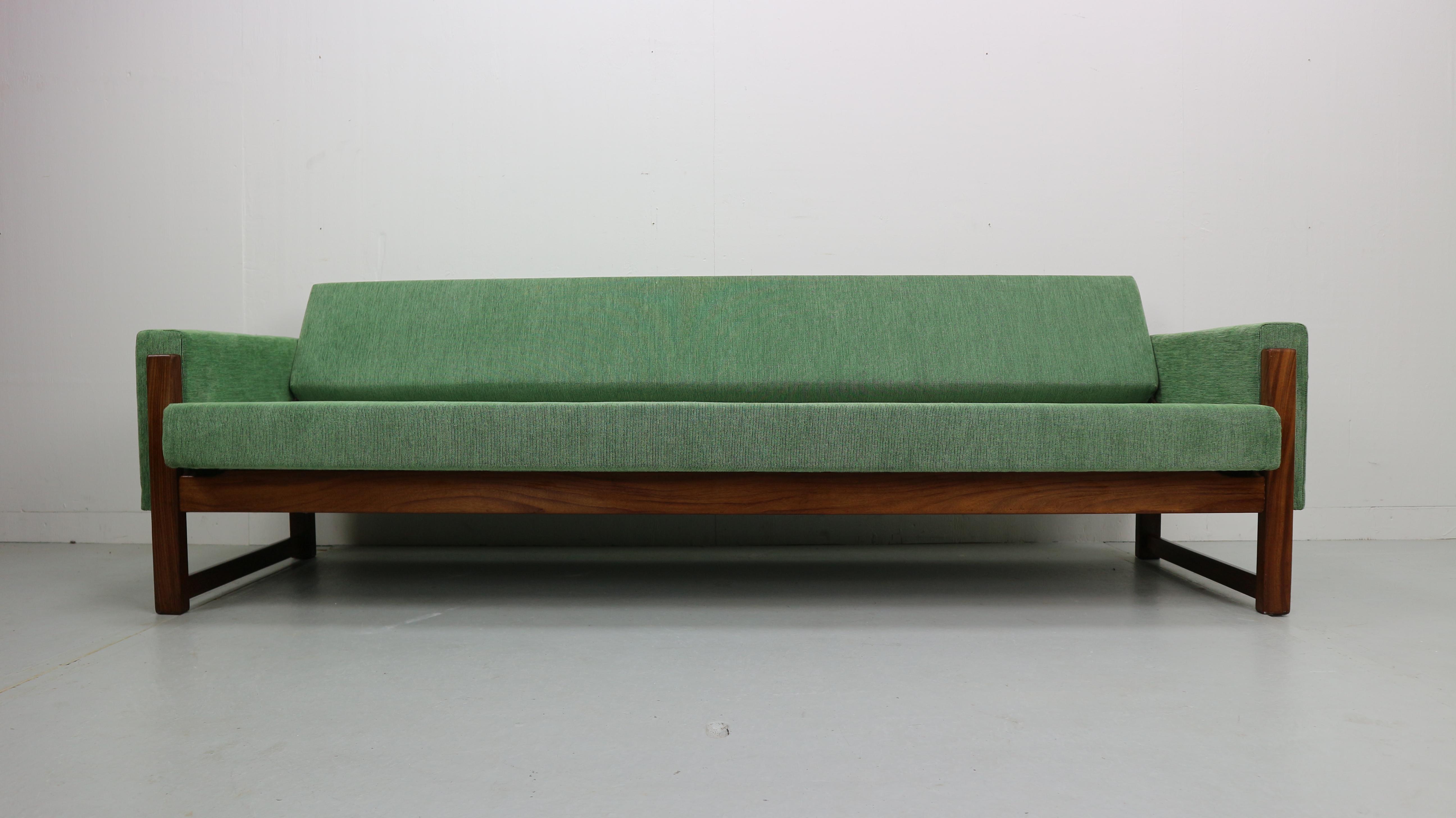This three-seat sofa-bed, model MX 01, was designed in the 1960s by Yngve Ekstrom and manufactured by Pastoe. It features a wooden frame and has new green upholstery. The sofa back can be reclined to be a bed.