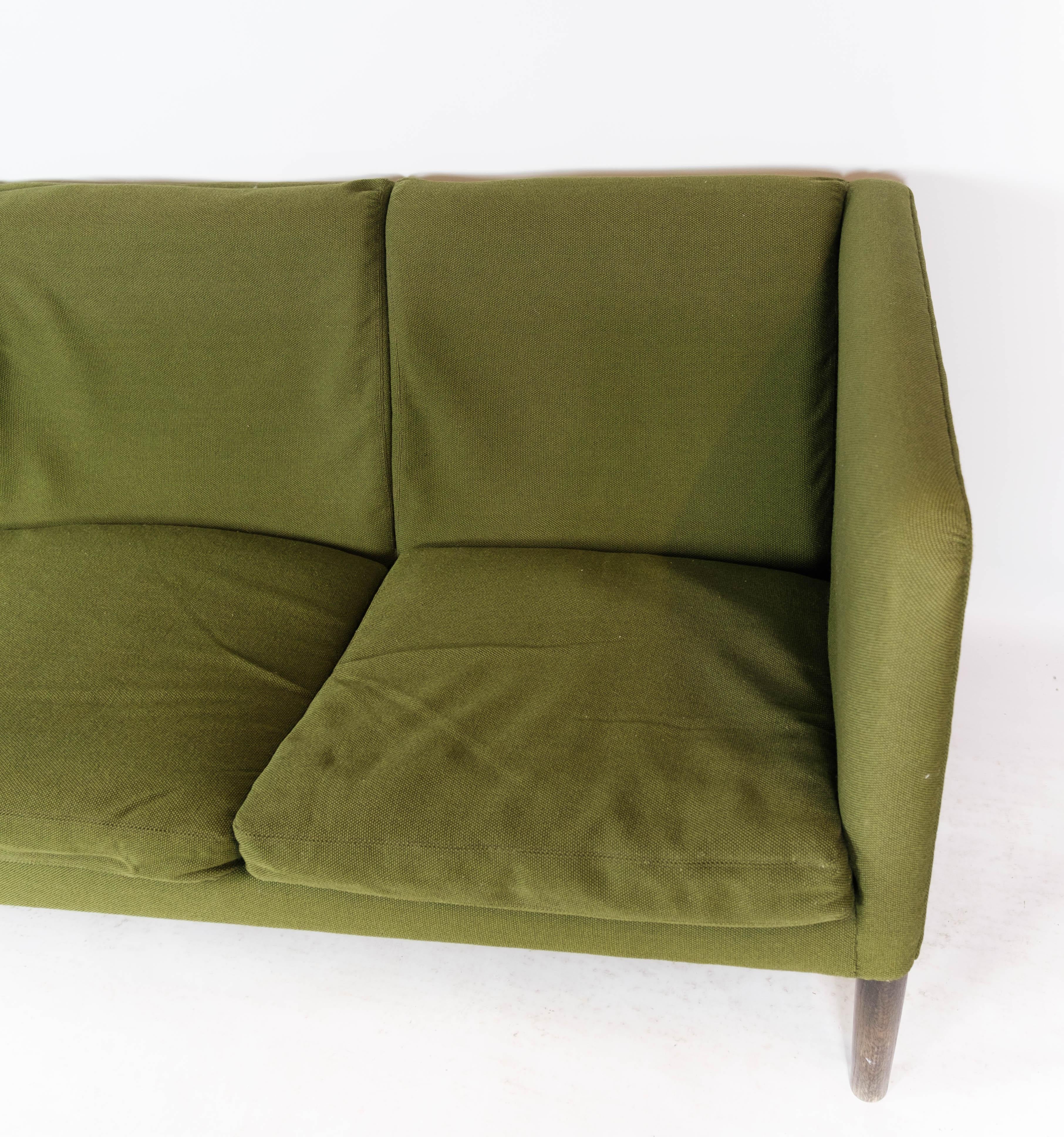 The three-seater sofa, Model AP 18S, upholstered in green wool fabric and with dark wood legs, was designed by the Danish architect Hans J. Wegner in 1960. Wegner, known for his unique contribution to Danish furniture design, created this sofa with