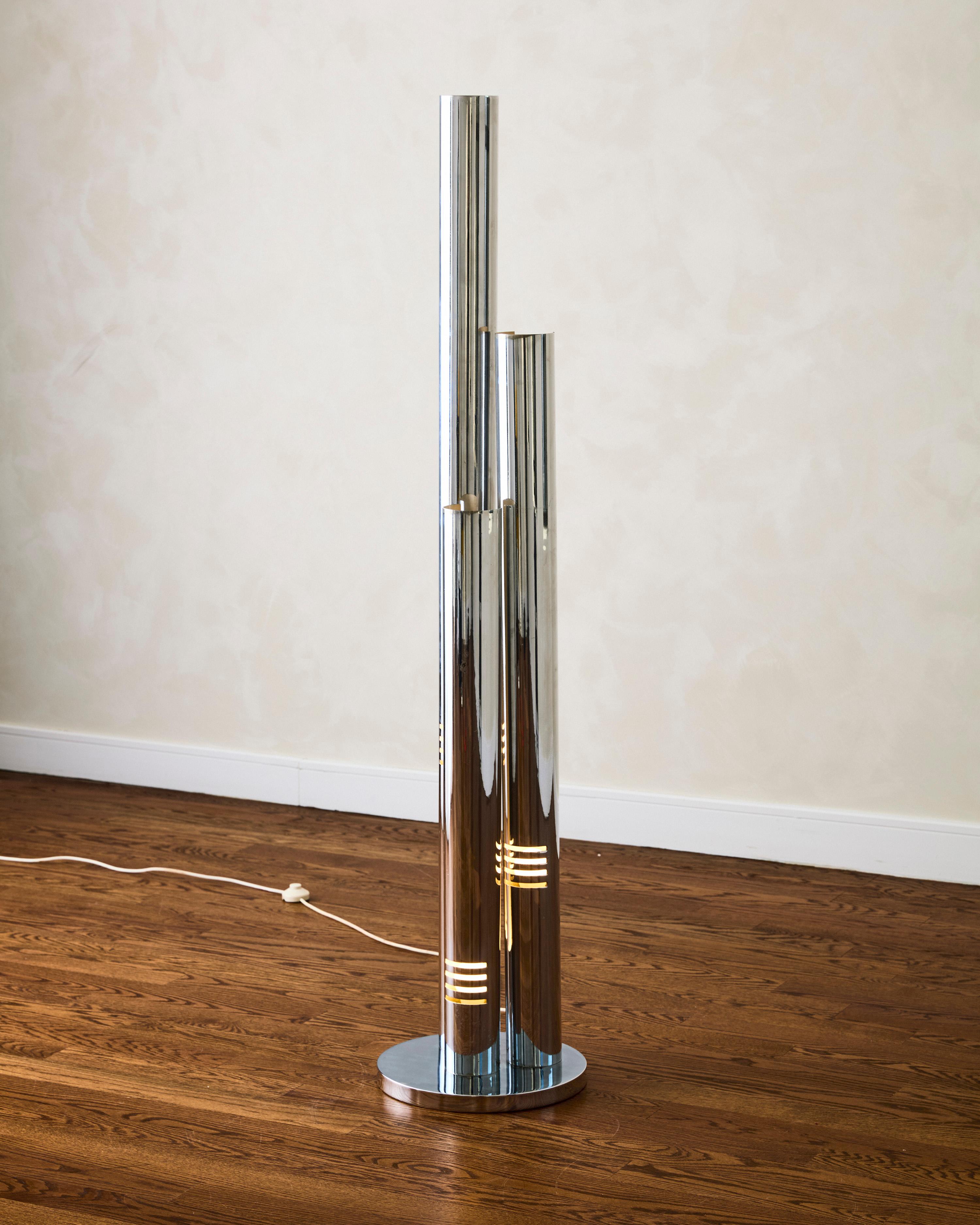 The Three-Shade Floor Lamp by Enrico Tronconi features a chrome-plated metal column structure with a white lacquered interior. Each column is adjustable by 360 degrees, allowing light to be directed in different directions.

