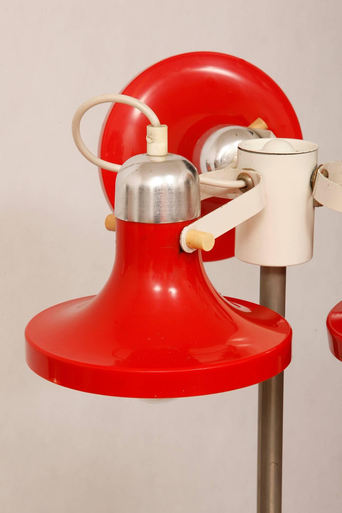 A red floor lamp that refers to the Space Age style from East Germany preserved in very good natural condition. Three rotating points of light mounted on a single arm. Heavy cast iron base. The lamp has a small wear abrasions of red lacquer visible