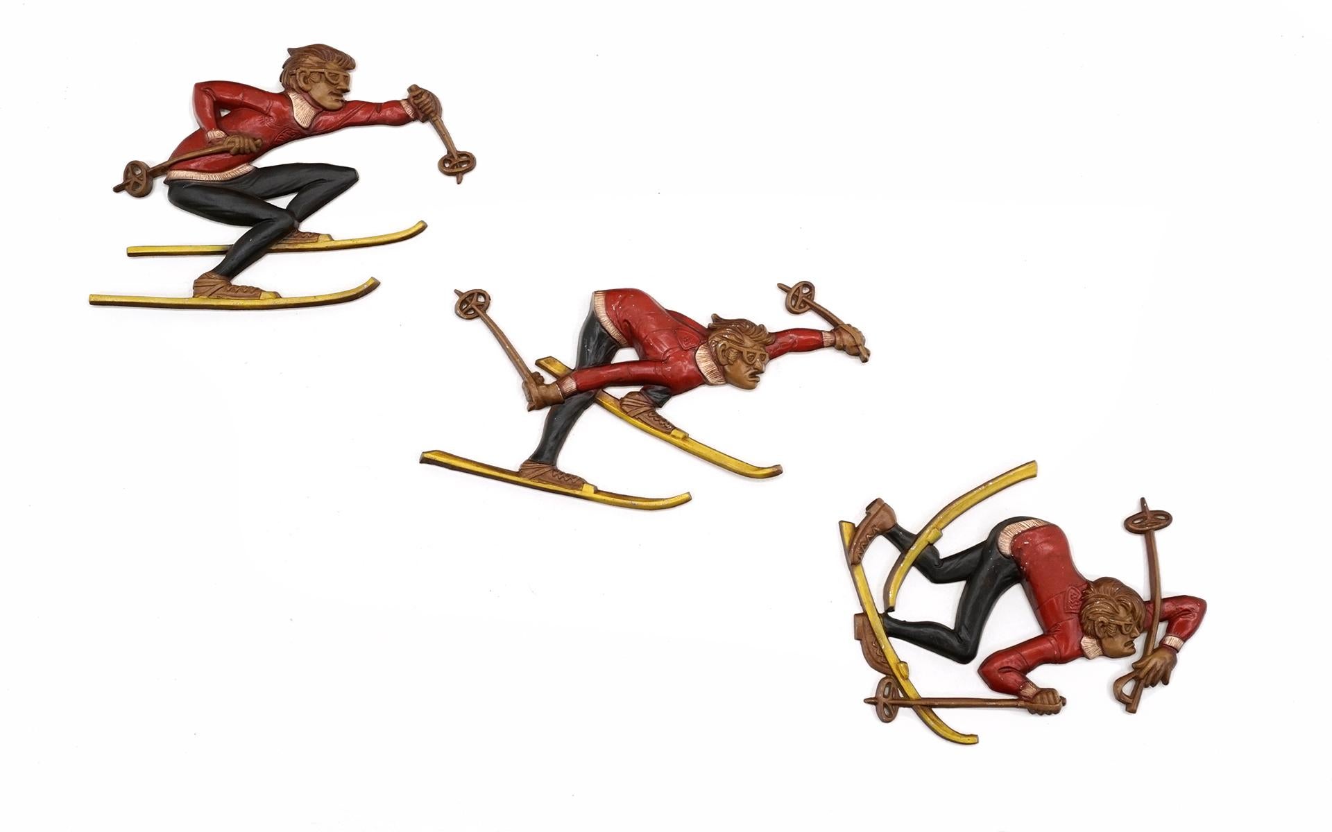 Fun set of metal wall sculptures featuring three skiers.  One skiing, one appearing to be going out of control and one falling.  Very cool hand painted set.  These would make the perfect gift foe the snow skier in your life.  All in very good