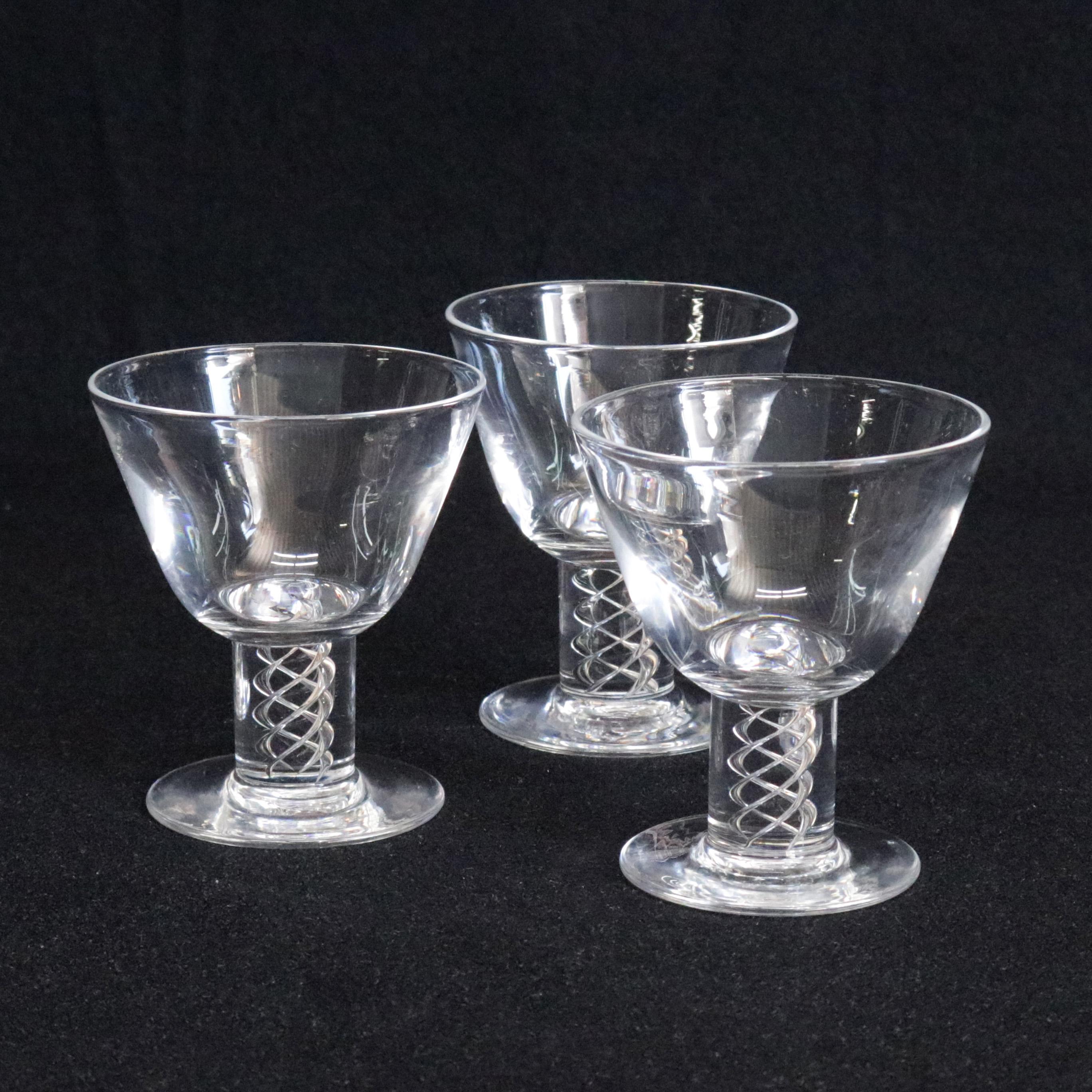 A set of three midcentury Steuben mouth blown crystal aperitif glasses or goblets feature colorless art glass with flared bowls and stems with air twist spiral designed in 1987 for Corning Museum of Glass, New York, NY, signed on bases, 20th