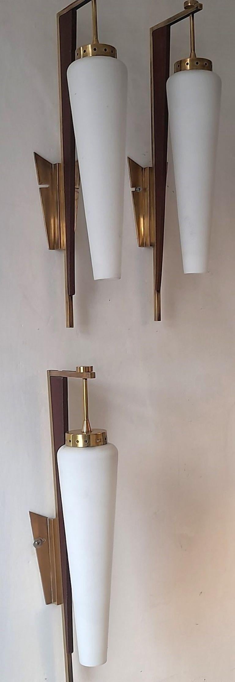 Set of three rare, tall wall lights by Stilnovo, Italy, 1950, modernist and clear lines design, brass galery with wood accents and opal glass shades. All three sconces in good original vintage condition, brass with some wear and aged patina,  no