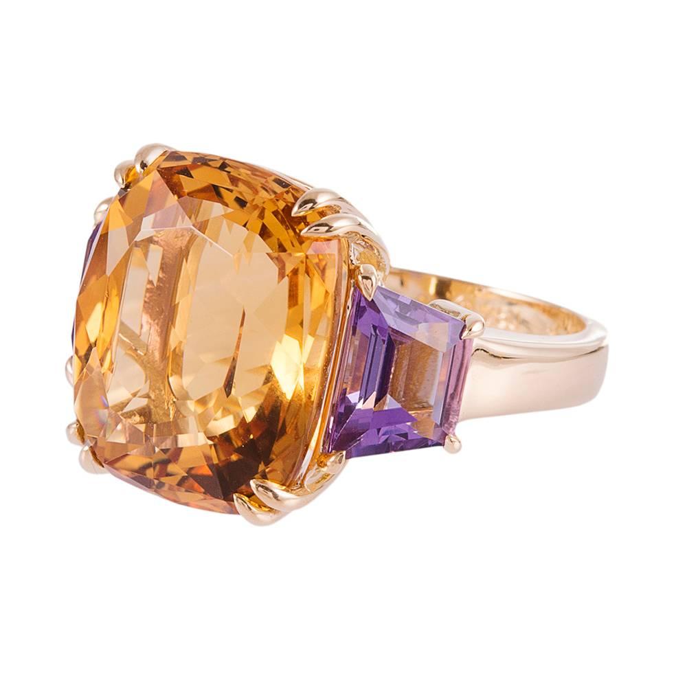 An antique cushion cut citrine weighing 13.42 carats, flanked by a pair of trapezoid amethysts that weigh 2.43 carats in total and assembled in ideal proportions, compliments of iconic American jeweler Seaman Schepps. Mounted in 18 karat yellow