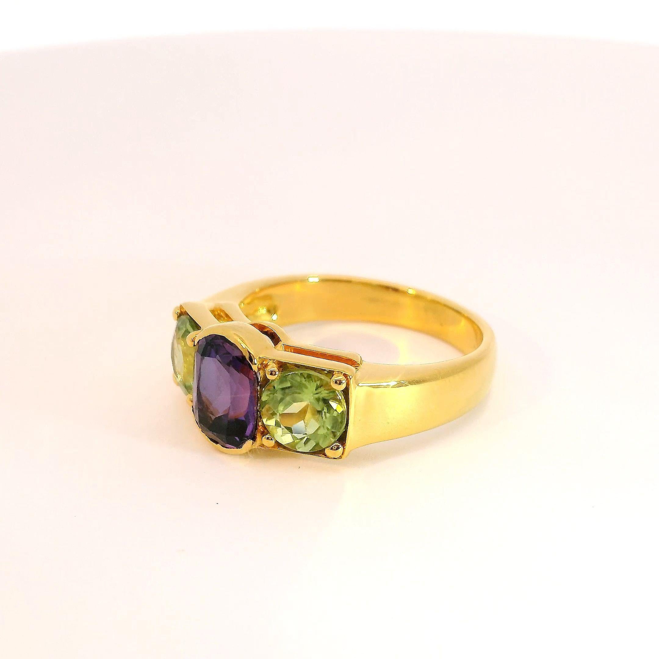 Contemporary Three-stone 1.45 carat Oval Amethyst and Round Peridot Ring in 18K Yellow Gold For Sale