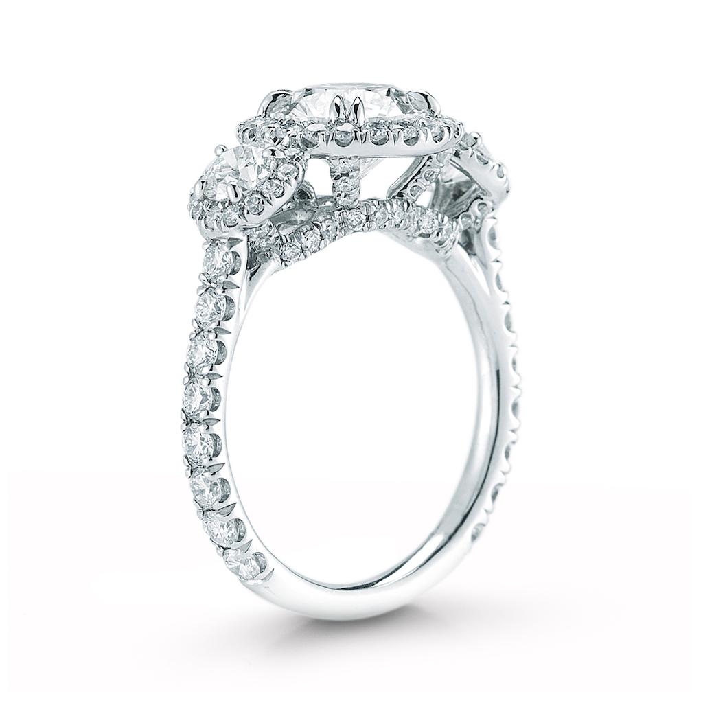 Simply elegant. A single halo embraces each round brilliant diamond in this handmade ring. Available in a range of center diamond sizes. 
Beauiful diamond ring features a round center stone in a halo setting and a pave band. Setting available in