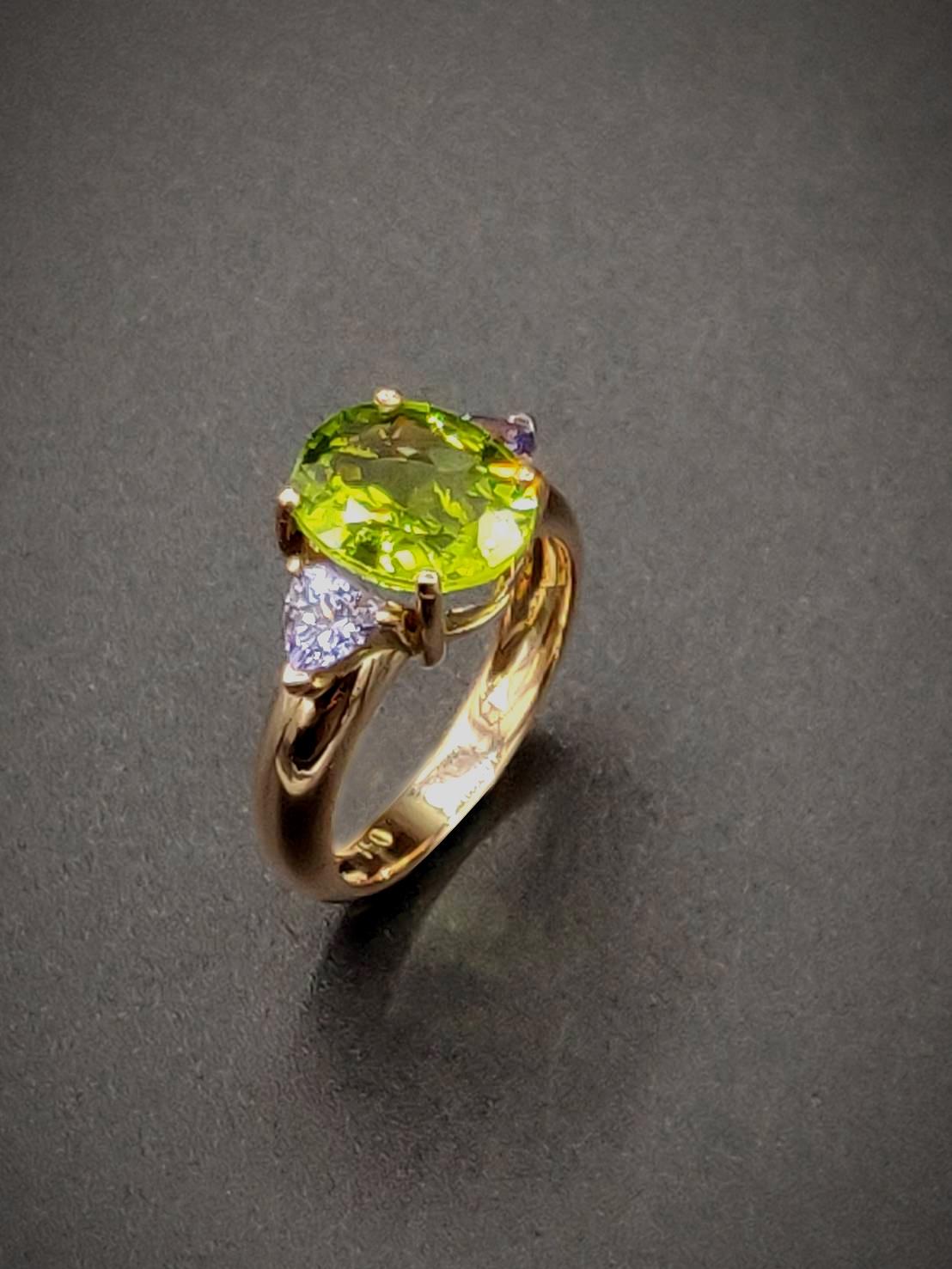 This simple three-stone 18K rose gold ring flaunts a 3.81ct good-sized oval vivid young leaf green peridot flattered by trillion light cornflower blue tanzanites on the flanks

Gold: 18K Rose Gold, 5.42 g
Peridot: Oval, 3.81 ct
Tanzanite: Trillion,