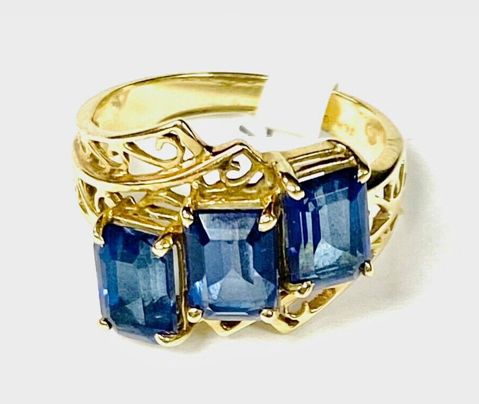 10k yellow gold three stone blue topaz ring, 3.59 Grams TW. The dimensions of the emerald cut stones are approximately 6 x 4.5 mm each. Approximately 0.75 carats each or a total of approximately 2.25 carats. Marked 10k. Approximate size 7.
