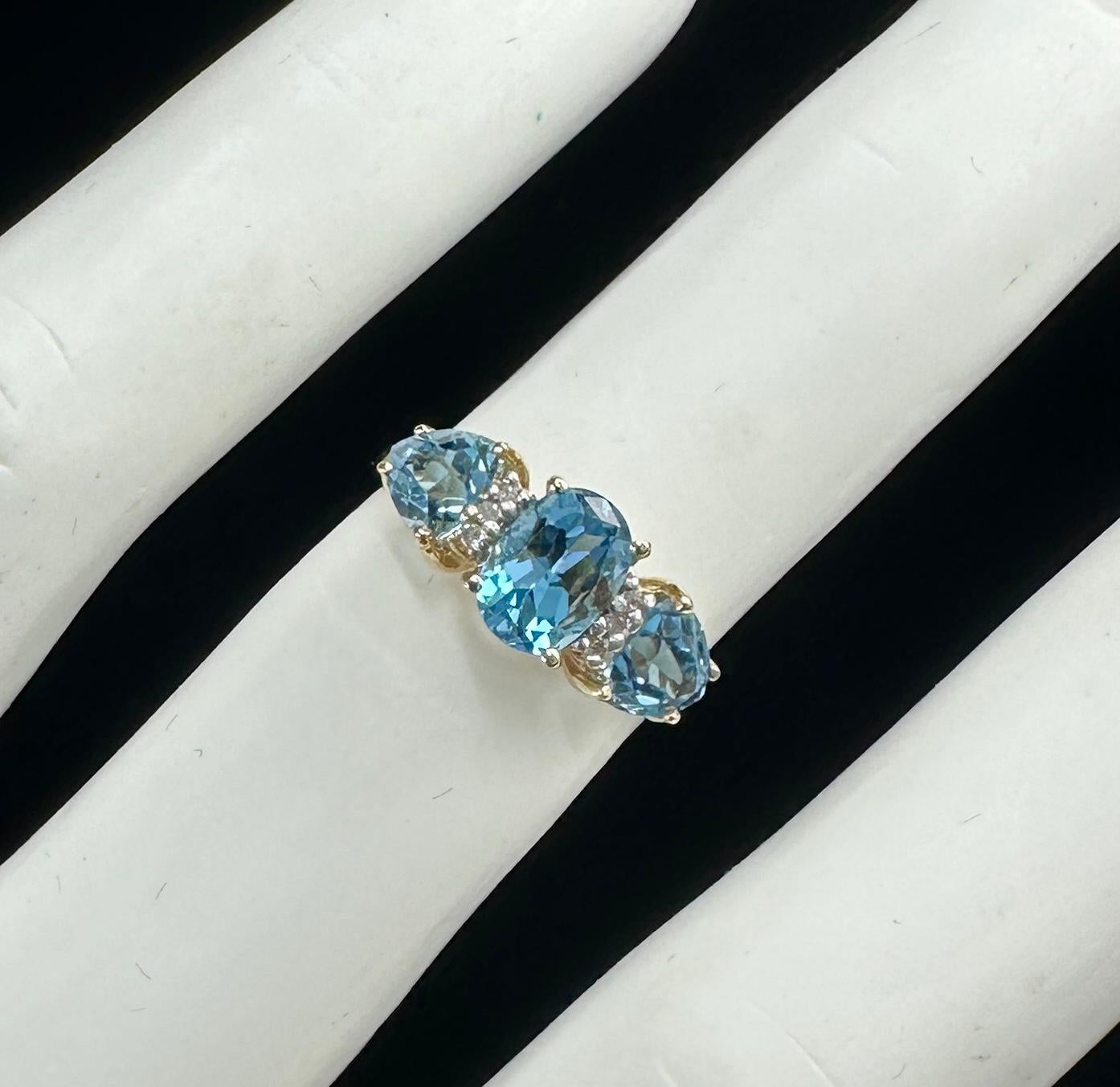 DIES IST EIN WUNDERSCHÖNER BLAUTOPASRING MIT 6 HERRLICHEN RUNDEN DIAMANTEN IM BRILLANTSCHLIFF IN EINEM SCHÖNEN DESIGN AUS 14 KARAT GELBGOLD.  
DER RING MIT DREI STEINEN HAT IN DER MITTE EINEN OVALEN, FACETTIERTEN BLAUTOPAS VON 1 KARAT UND AN BEIDEN