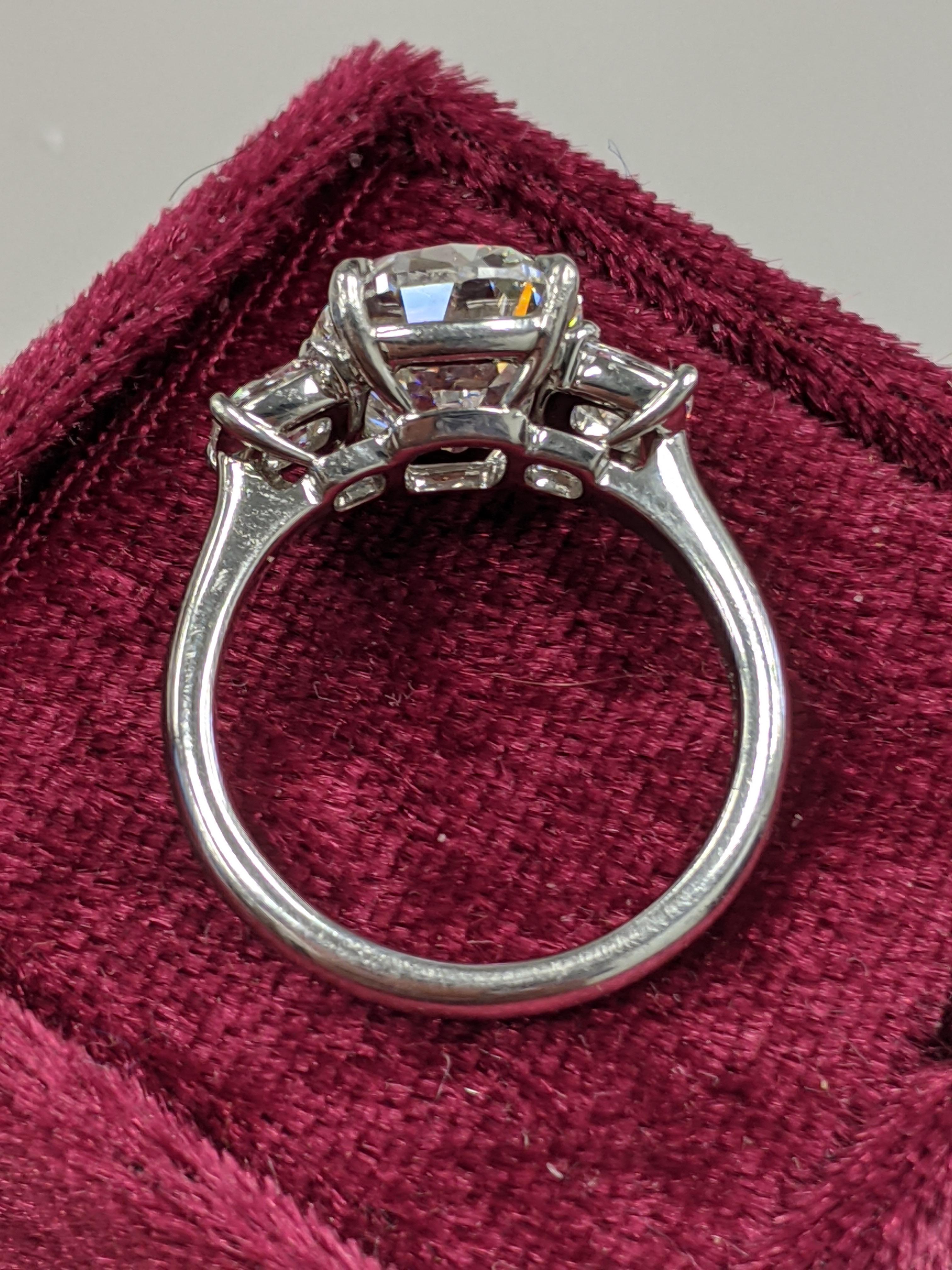 The perfect five star ring no matter where you travel internationally.  This four carat G color VS2 clarity Traditional Cushion Brilliant diamond is flanked by smaller cushions (0.60+ ctw) The mounting is platinum by one of the top setting jewelers