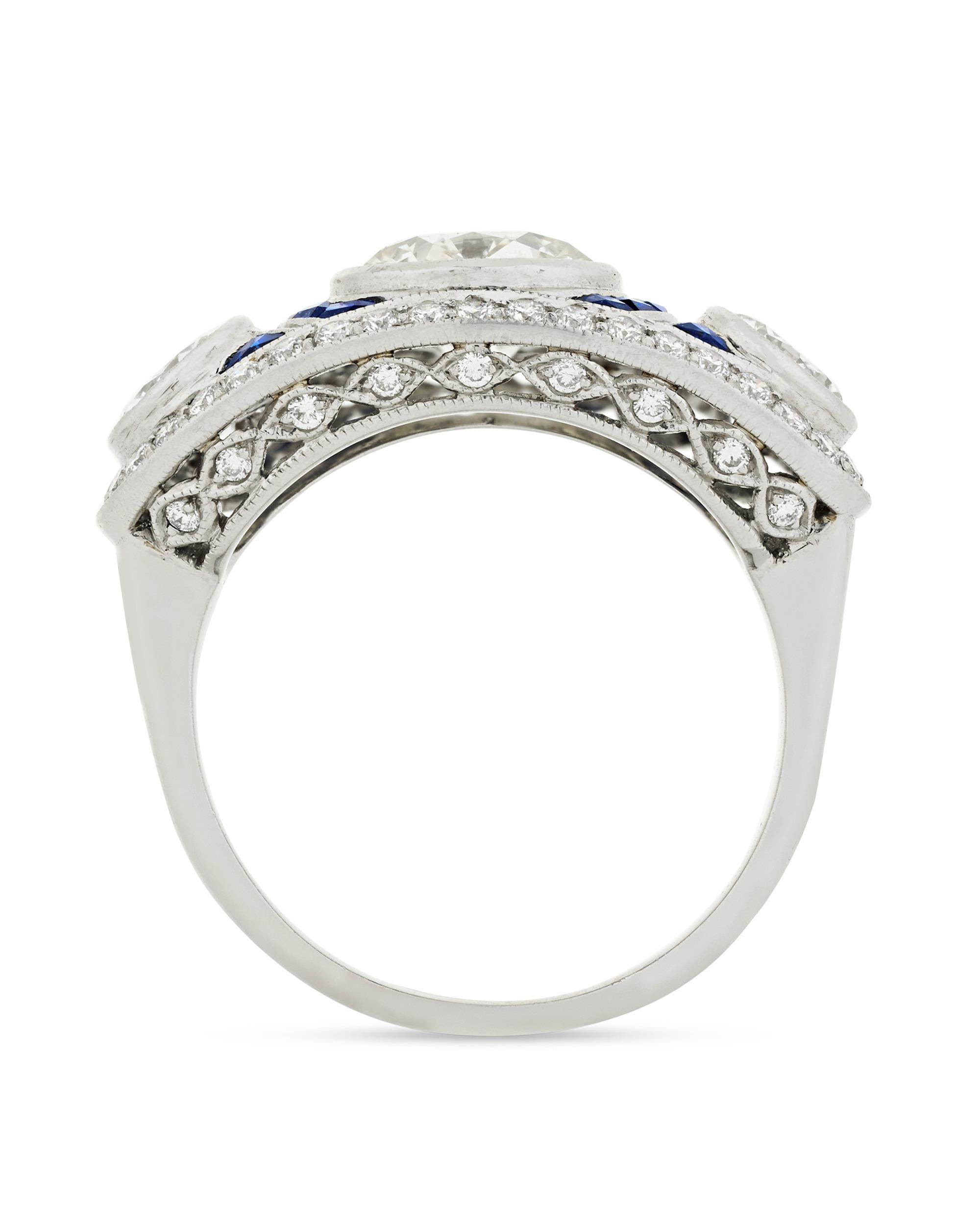Three amazing diamonds are the stars of this ring inspired by the glamor of the Art Deco period. The jewels weigh a combined 2.40 carats and are separated by velvety blue sapphires. .50 carat of diamond accents add even more sparkle to this glorious