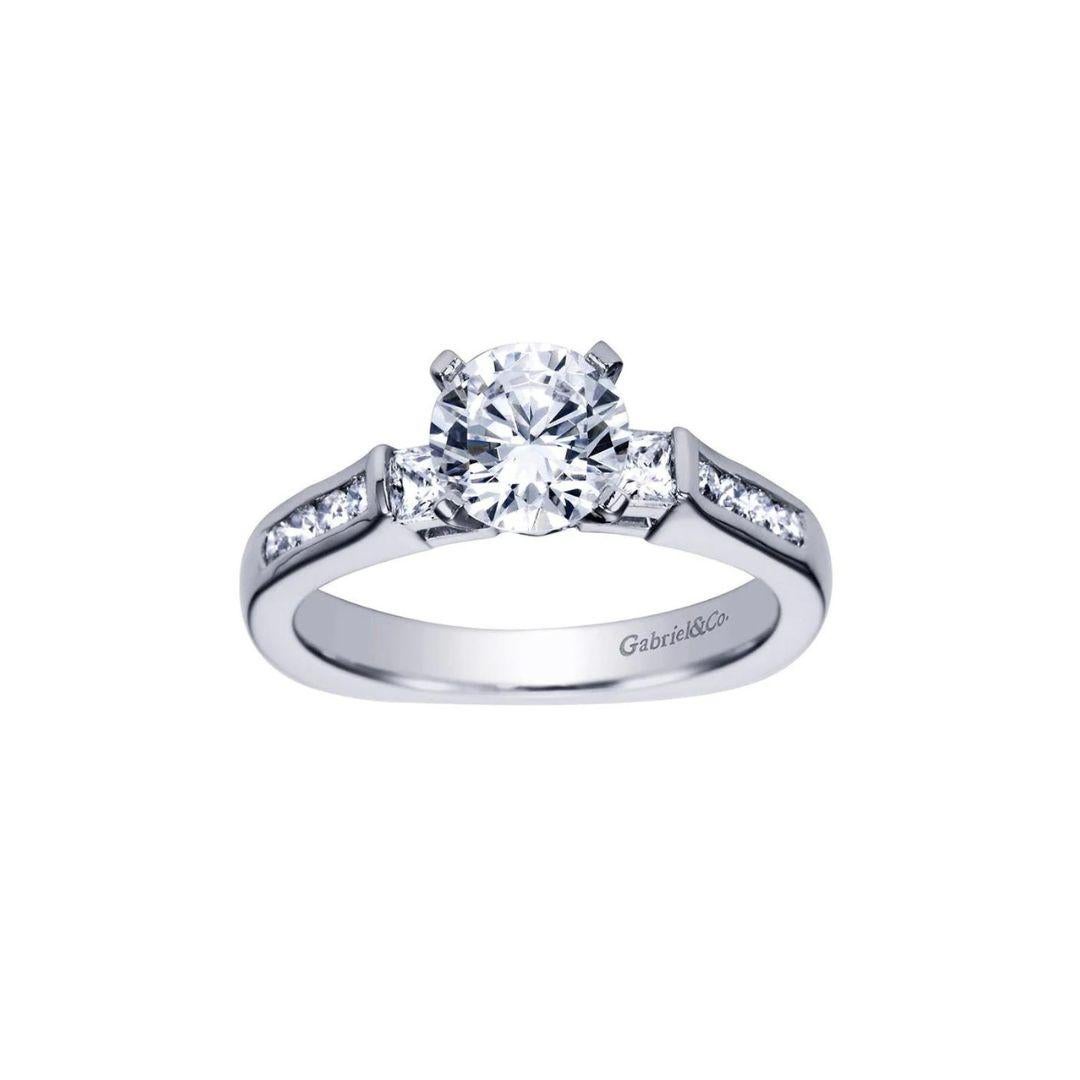 Traditional Three Diamonds Channel Set Engagement Mounting in 14k white gold. Classic channel set sides lead up to two princess cut diamonds, flanking the center stone. Center diamond NOT included. Side diamonds weigh a total carat weight of 0.55