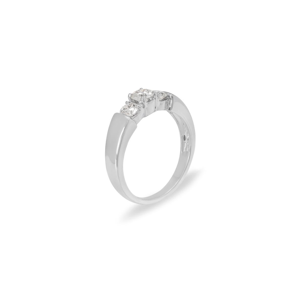 A classic 18k white gold diamond three stone ring. The ring is set to the centre with a round brilliant cut diamond with an approximate weight of 0.30ct, G-H colour and VS clarity. Accentuating the centre stone are single round brilliant cut