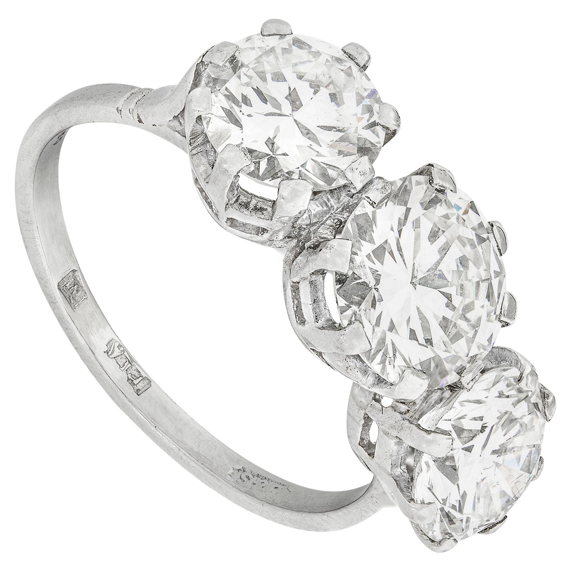 A three-stone diamond ring, the three round brilliant-cut diamonds weighing 1.51, 1.25 and 1.15 carats, respectively of  H, F and H colour, VS1, VS2 and I1 clarity,  certified AnchorCert , all claw-set in platinum to a D-section shank, hallmarked