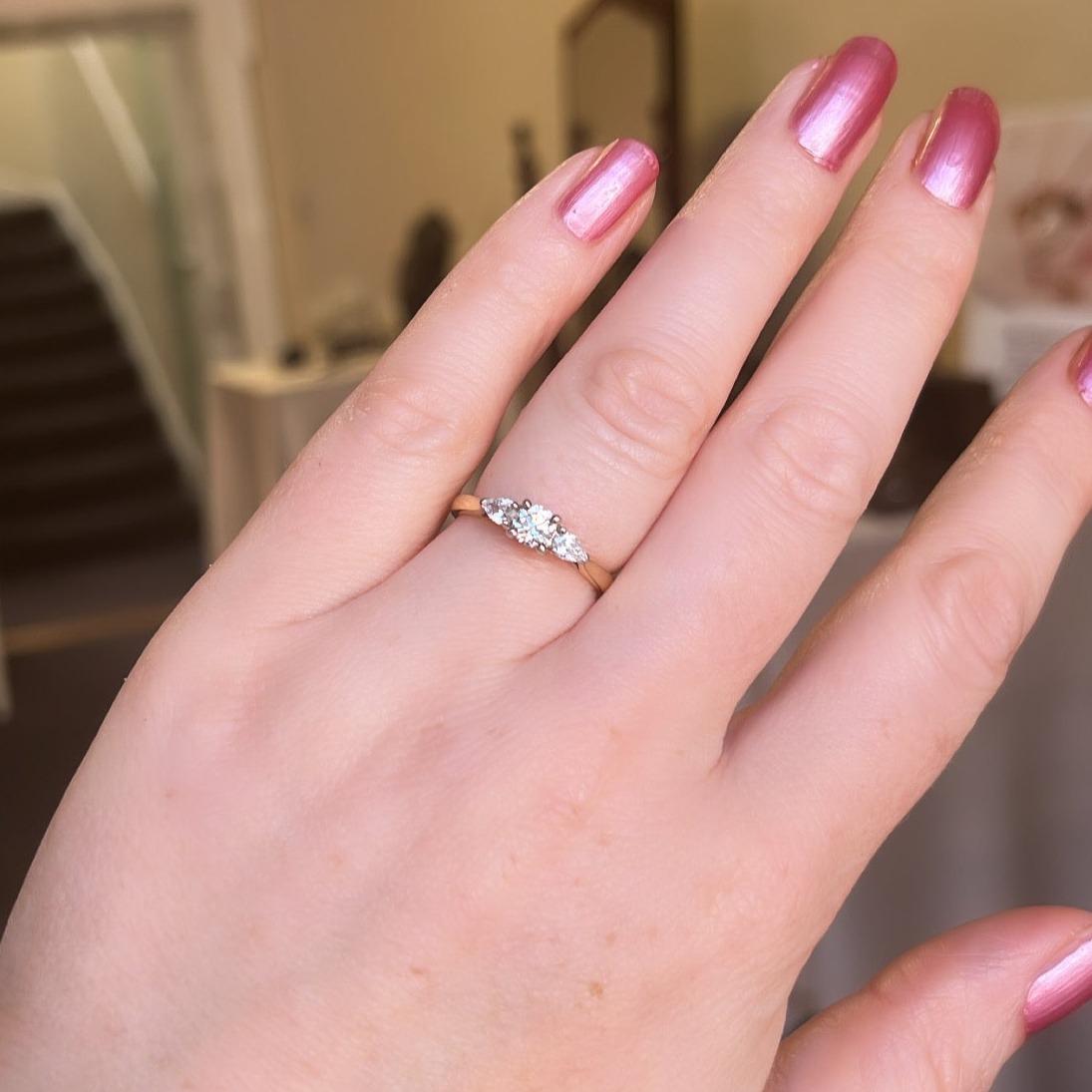 A classic style with a twist, this unique three stone diamond ring is flattering on every hand.  Set with a round brilliant cut in the centre held in with four prongs and accented on either side with a sparkling pear cut dimaond.  The diamonds are