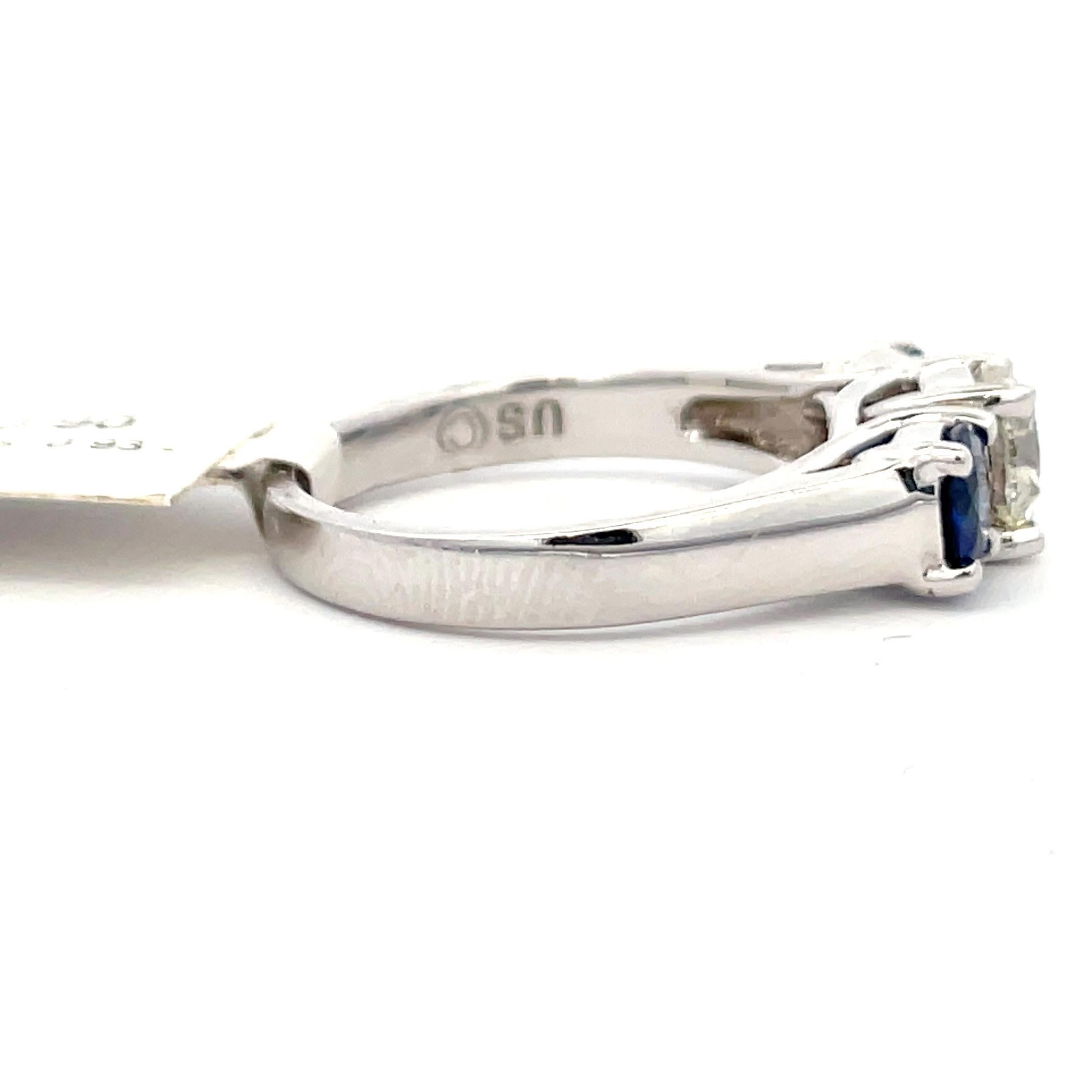 14 Karat White gold three stone ring featuring one round brilliant weighing 0.68 carats and two blue Sapphires weighing 0.73 carats.
