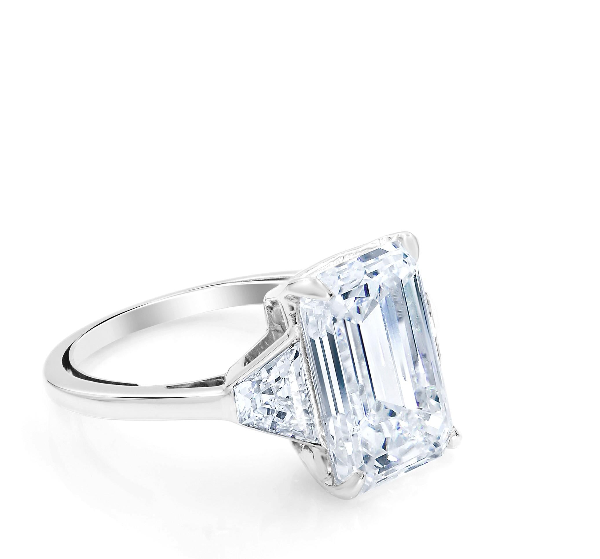 A bright icy-white, sleekly modeled emerald-cut diamond, weighing 5.05 carats, scintillates between a matched pair of trapezoidal cut diamonds creating a fabulous seamless flash of light atop this chic, sophisticated, and stunning classic three