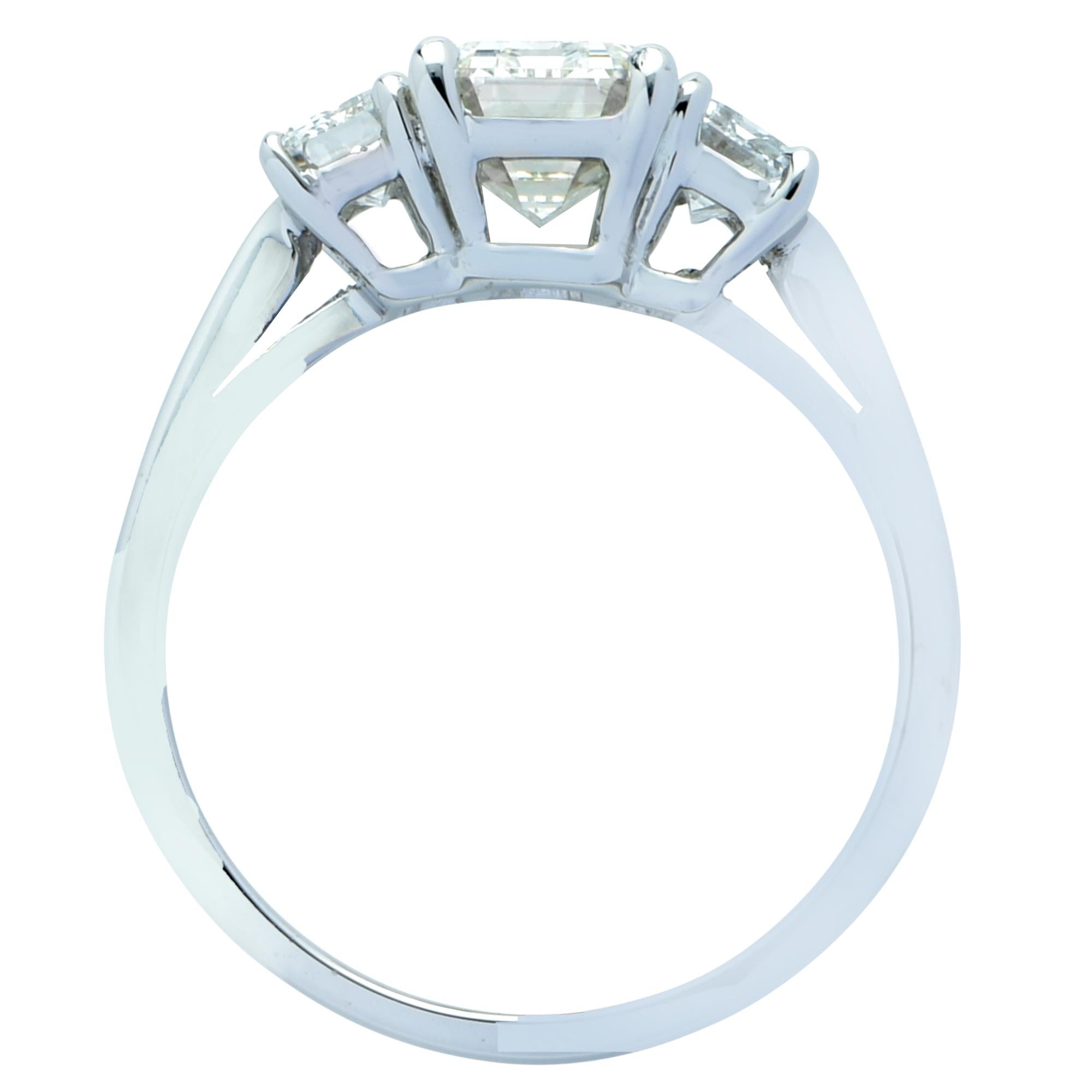 Exquisite engagement ring crafted in platinum, showcasing a gorgeous emerald cut diamond weighing 1.79 carats, K color, VS1 clarity, adorned with two emerald cut diamonds weighing .82 carats total, J color, VS2 clarity. The seamless face of this