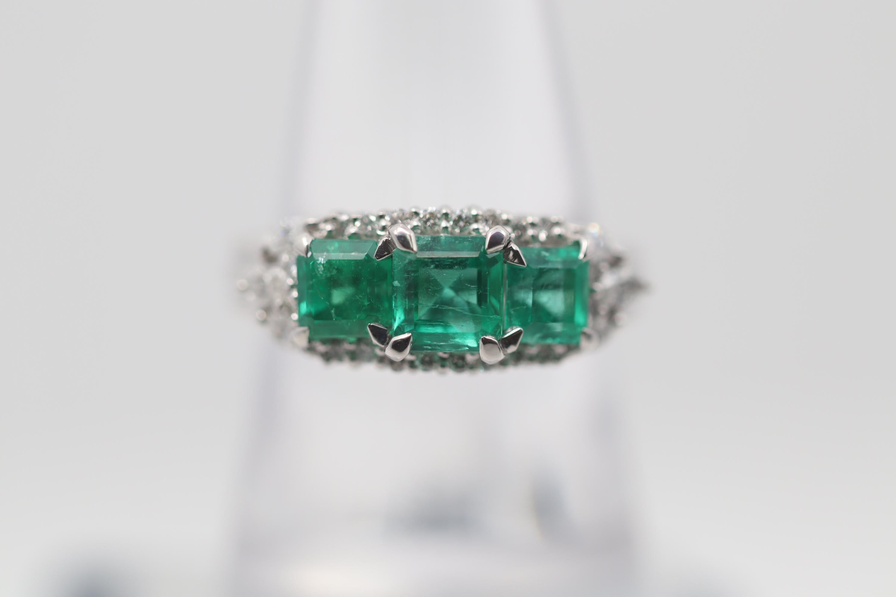 Three superb gem-quality emeralds set side by side steal the show! They weigh a total of 1.88 carats and have a rich clean grass green color with excellent brightness. They are accented by 0.45 carats of round brilliant-cut and marquise-shaped