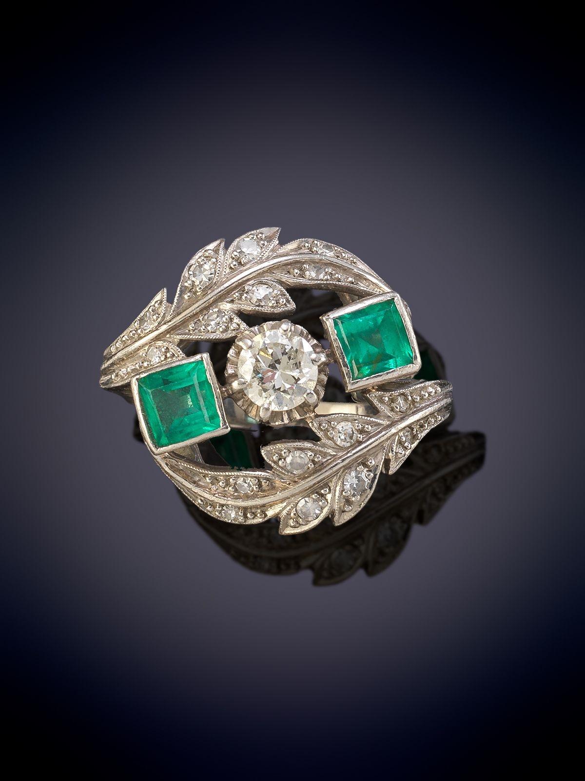 Three Stone Diamond and Emerald Ring. Mounted in Platinum.
Two are better than one! In this sleek and stunning estate jewel, a seamlessly-set pair of gorgeous, gemmy, rich crystalline green Colombian emeralds  - together weighing 1.30 carats -