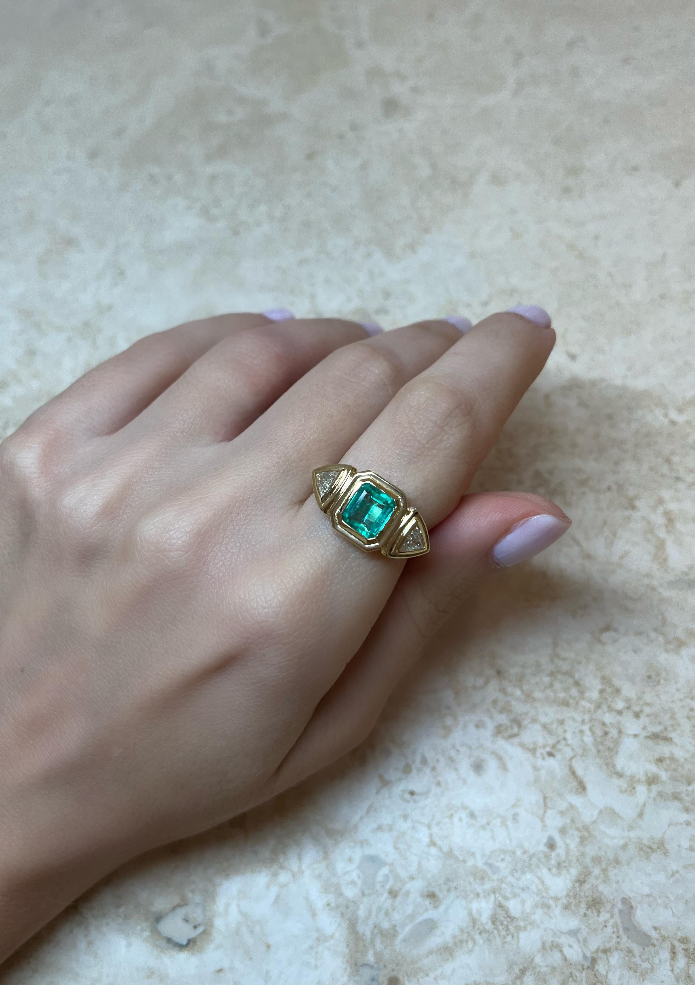 This exquisite 18-karat gold ring is centered with a natural emerald and paired with two natural trillion-cut diamonds, in a geometric stepped setting. 

The ring weighs just over 6grams of gold, giving it a luxurious feel. It's three stone design