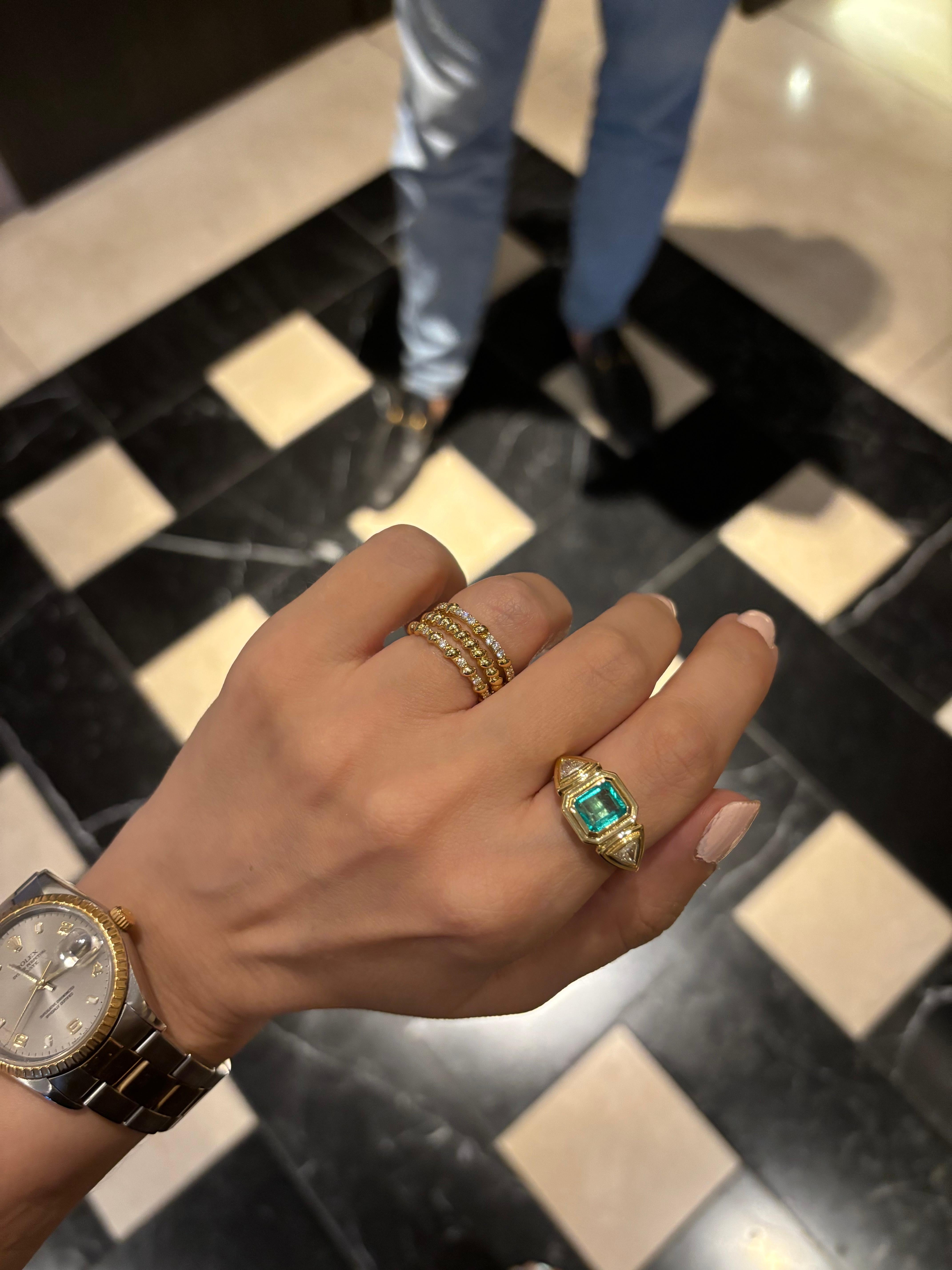 This exquisite 18-karat gold ring is centered with a natural emerald and paired with two natural trillion-cut diamonds, in a geometric stepped setting. 

The ring weighs just over 6grams of gold, giving it a luxurious feel. It's three stone design