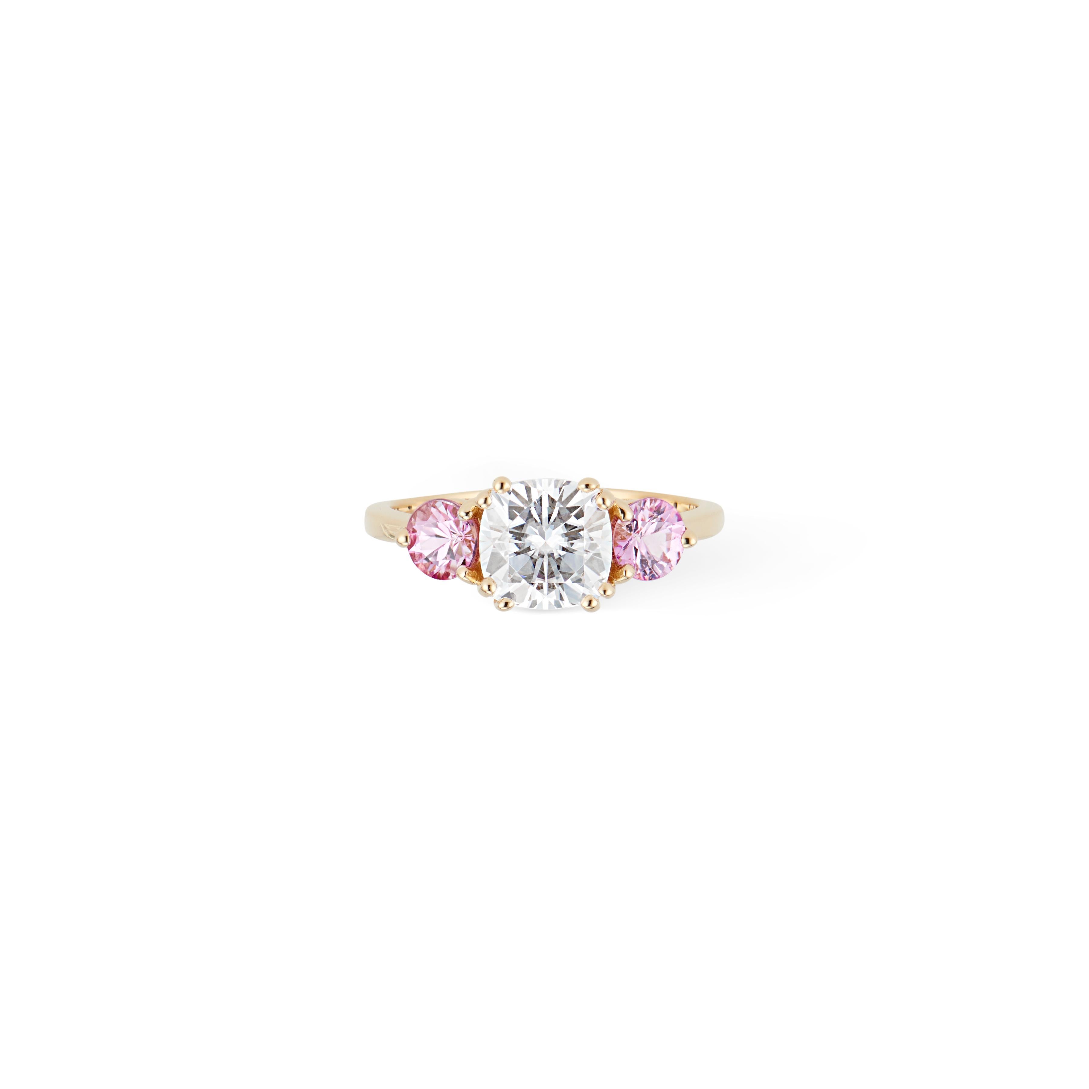 Gorgeous 1.5 carat Cushion Cut Moissanite accented with two Natural Pink Sapphires set in a high polish 14k yellow gold setting.

Three stone Engagement rings are enjoying a huge moment of popularity currently and 
are said to be symbolic of the