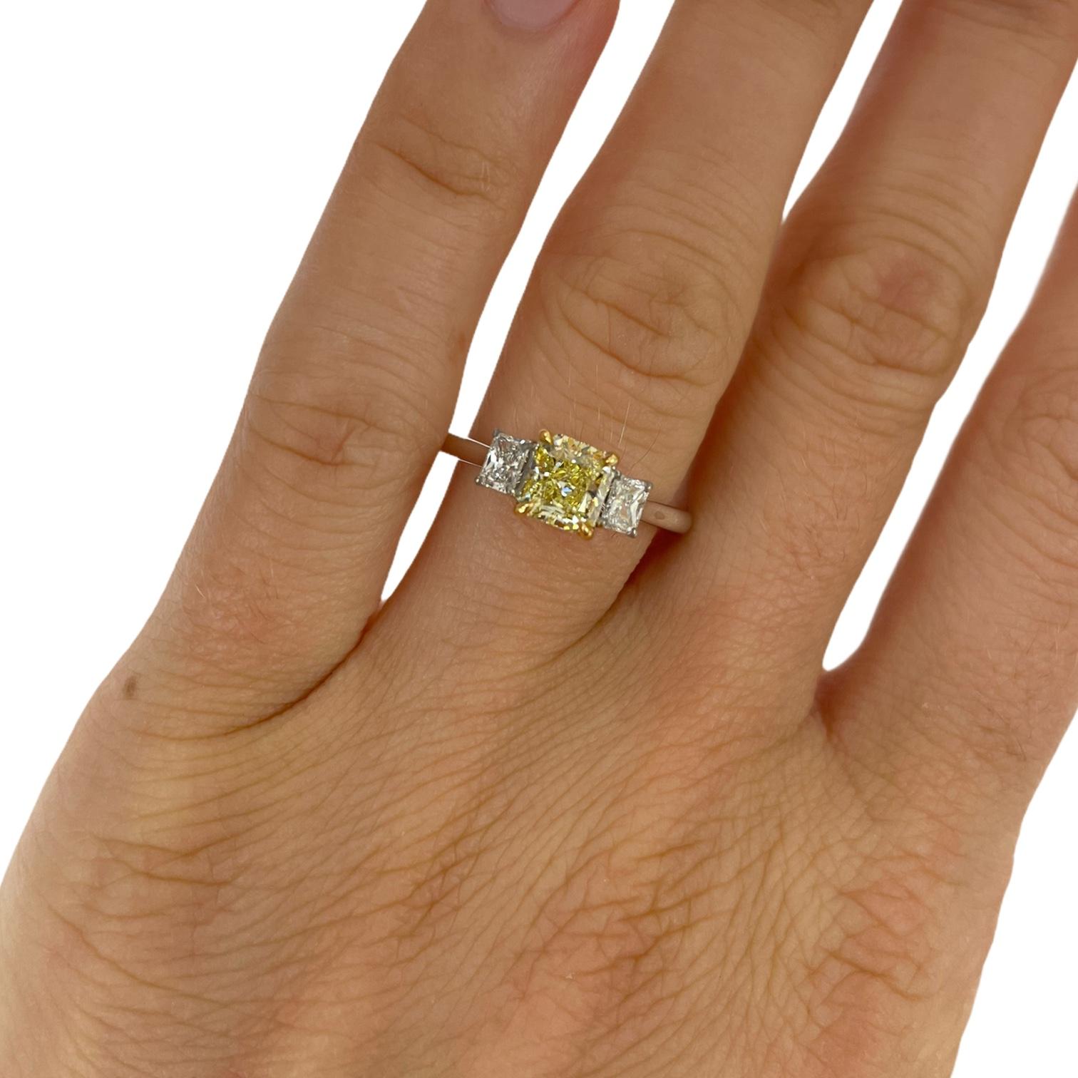 Ladies three stone fancy yellow and white diamond ring in 18k white gold. Ring contains 1 center radiant cut fancy yellow diamond, 1.02cts and 2 side radiant cut white diamonds, 0.31tcw. Center fancy yellow diamond is GIA certified.. Side white