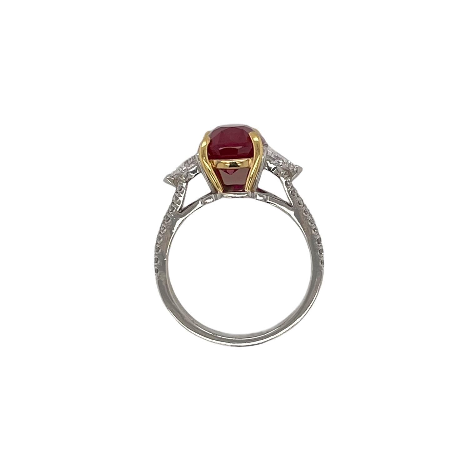 Stunning three stone ruby and diamond ring in 18k yellow gold & platinum. Ring contains 1 center oval ruby 5.00cts, 2 kite shaped diamonds 1.05tcw and round brilliant diamonds on band, 0.25tcw. Center ruby originates from Mozambique and has a pigeon