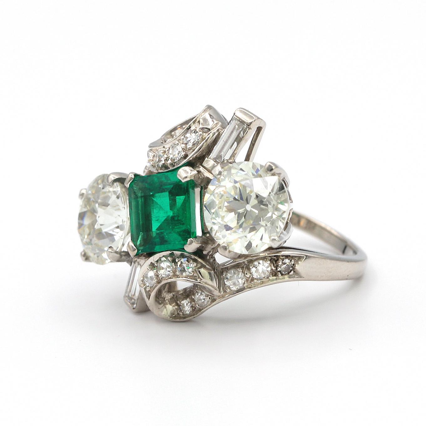 5.45 Total carat weight of white diamonds (two 2.50 carat round diamonds, 2 baguette .10 carat each, and 15, .05ct round diamonds). 

The center is a beautiful green emerald, approximately 2.00 carats (7.08mm x 7.15mm).
It is mounted in platinum and