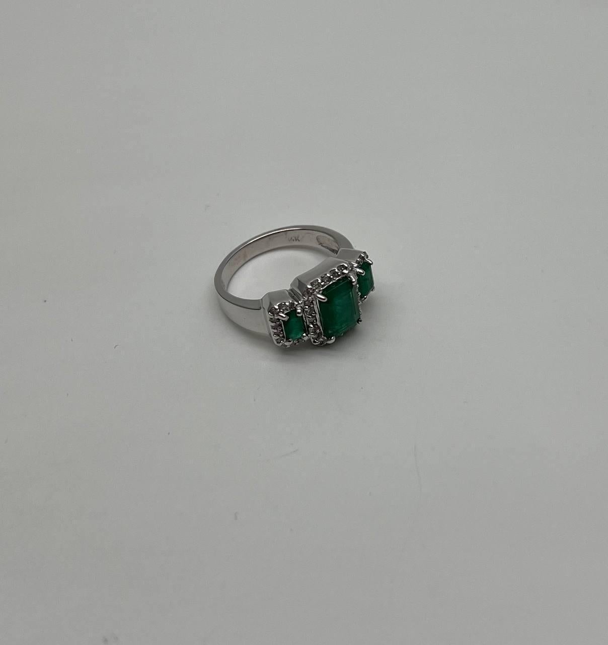 A sophisticated ring featuring three rectangular green emerald, each surrounded by a halo of small, sparkling accent diamonds.
The central stone is slightly larger, creating a focal point, while the two side stones complement it perfectly.
Crafted