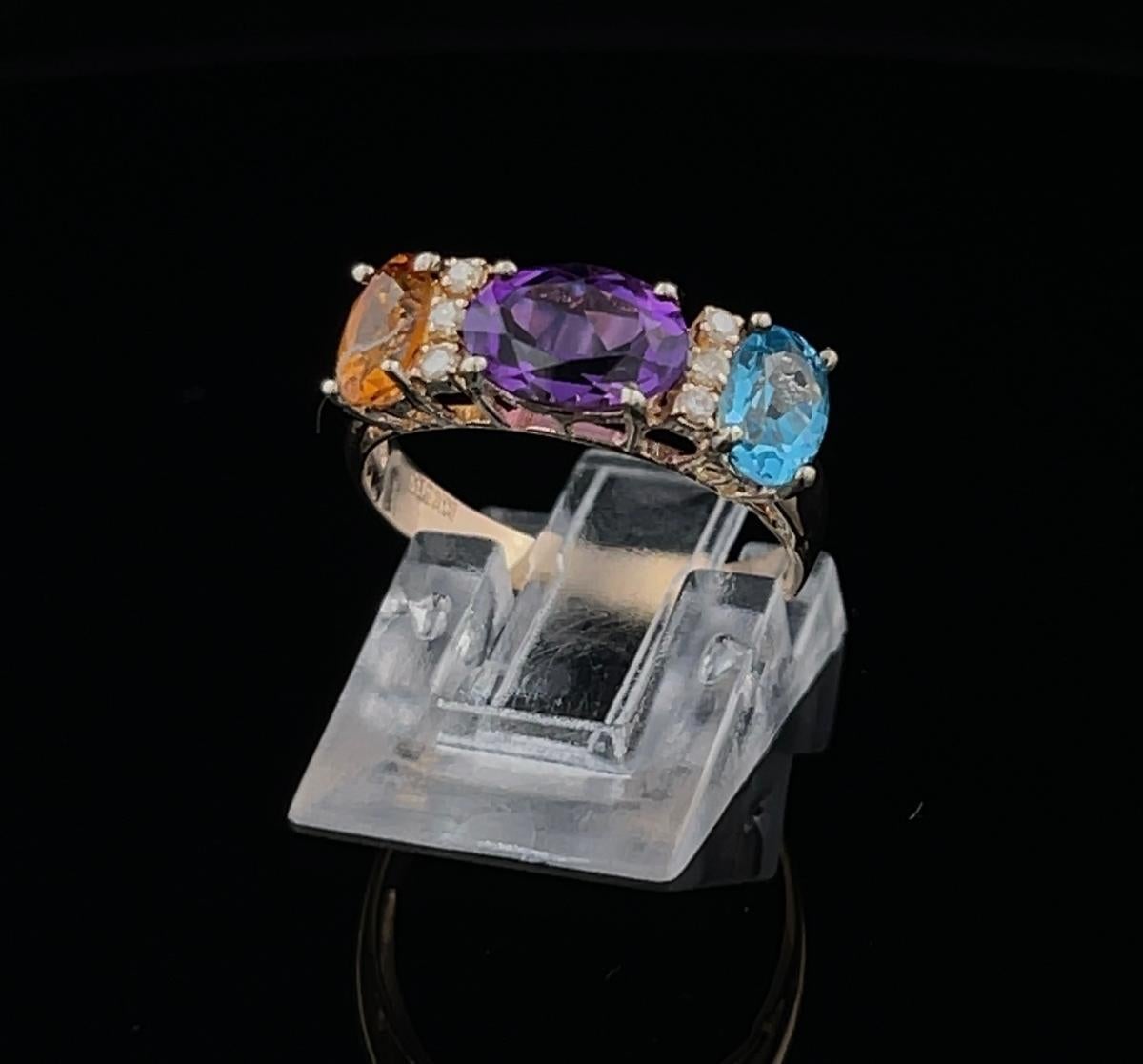 Beautiful multi colored gem colored ring for everyday! 

Don't miss out on wearing this three stone and diamond ring in 14K Yellow Gold. 
The ring hold a 6x8MM Oval Amethyst (weighing 1.50CT approx.), 6x4MM Oval Blue Topaz (weighing 1.00CT approx.),