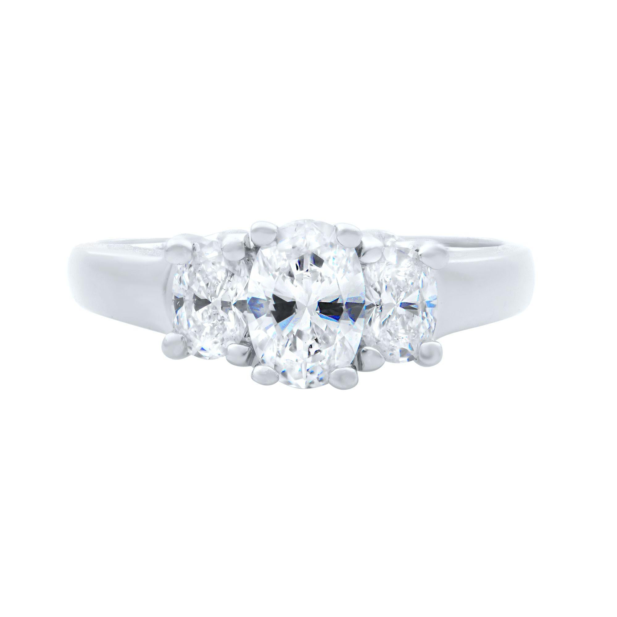 This classic three-stone engagement ring is crafted in quality 14k white gold which boasts three oval-shaped diamonds at approximately 1.10 carat total weight. Each stone is secured with four prongs. Diamonds are VS2 clarity and H color. Ring size